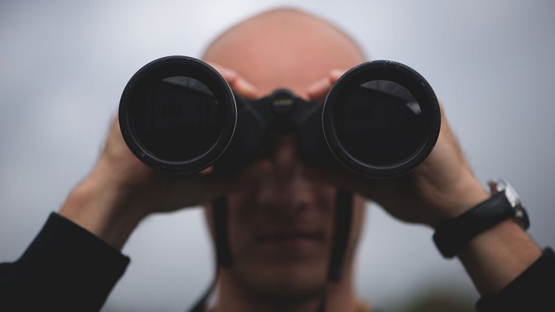 Ein Mann blickt durch ein Fernglas in die Ferne, wobei sein Gesicht unscharf und das Fernglas im Fokus ist. | Bild: stock.adobe.com/Zelma Ein Mann blickt durch ein Fernglas in die Ferne, wobei sein Gesicht unscharf und das Fernglas im Fokus ist.