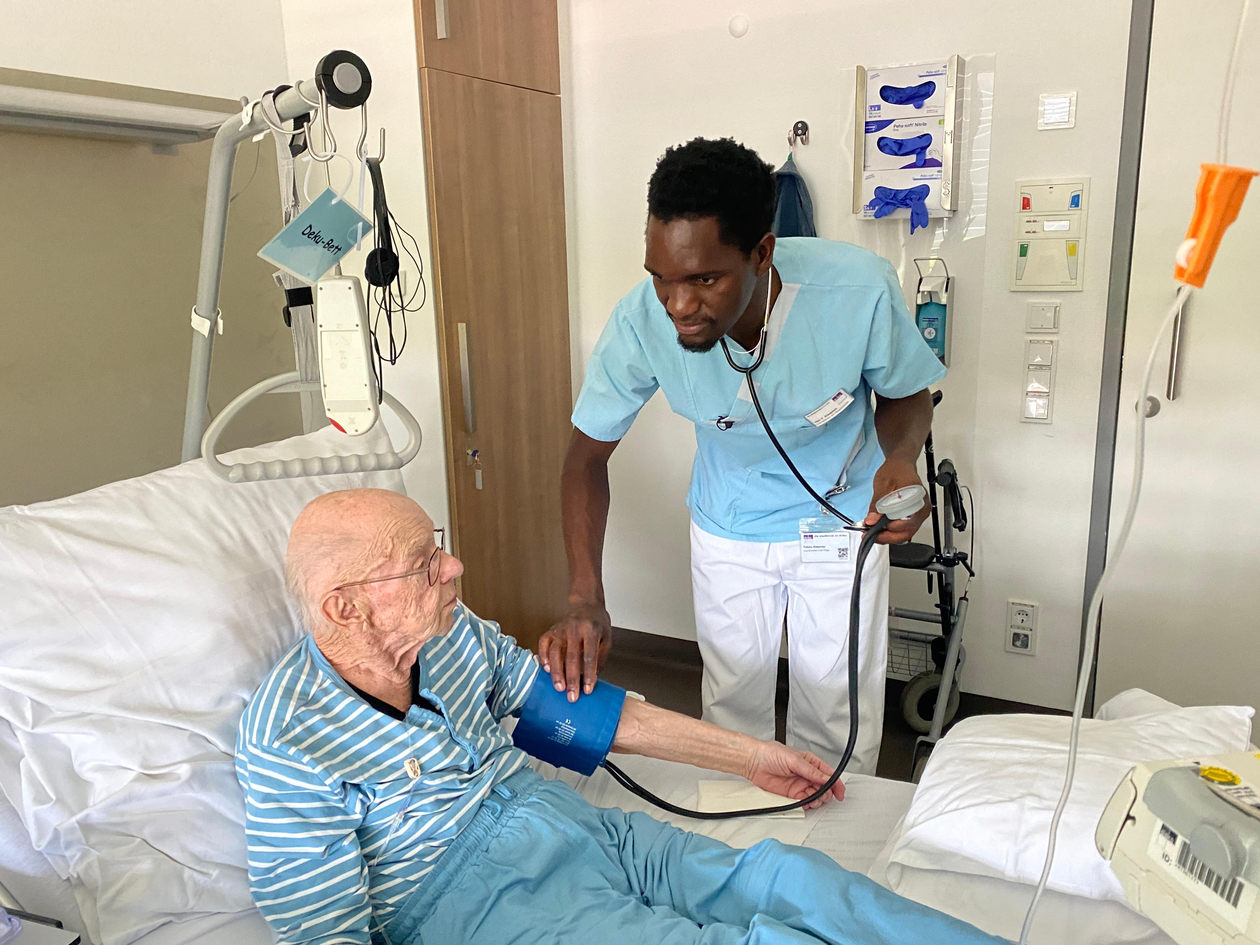 Faluka Kiweewa bei der Arbeit: Blutdruckmessen bei einem Krebspatienten