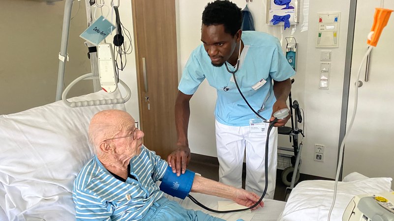 Faluka Kiweewa bei der Arbeit: Blutdruckmessen bei einem Krebspatienten