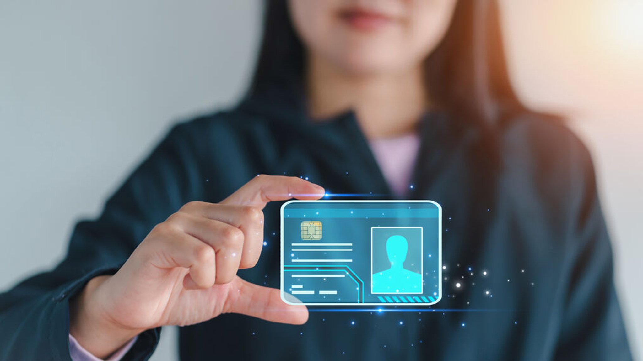 Eine Frau hält eine transparente digitale Ausweiskarte mit Hologrammeffekt in der Hand.
