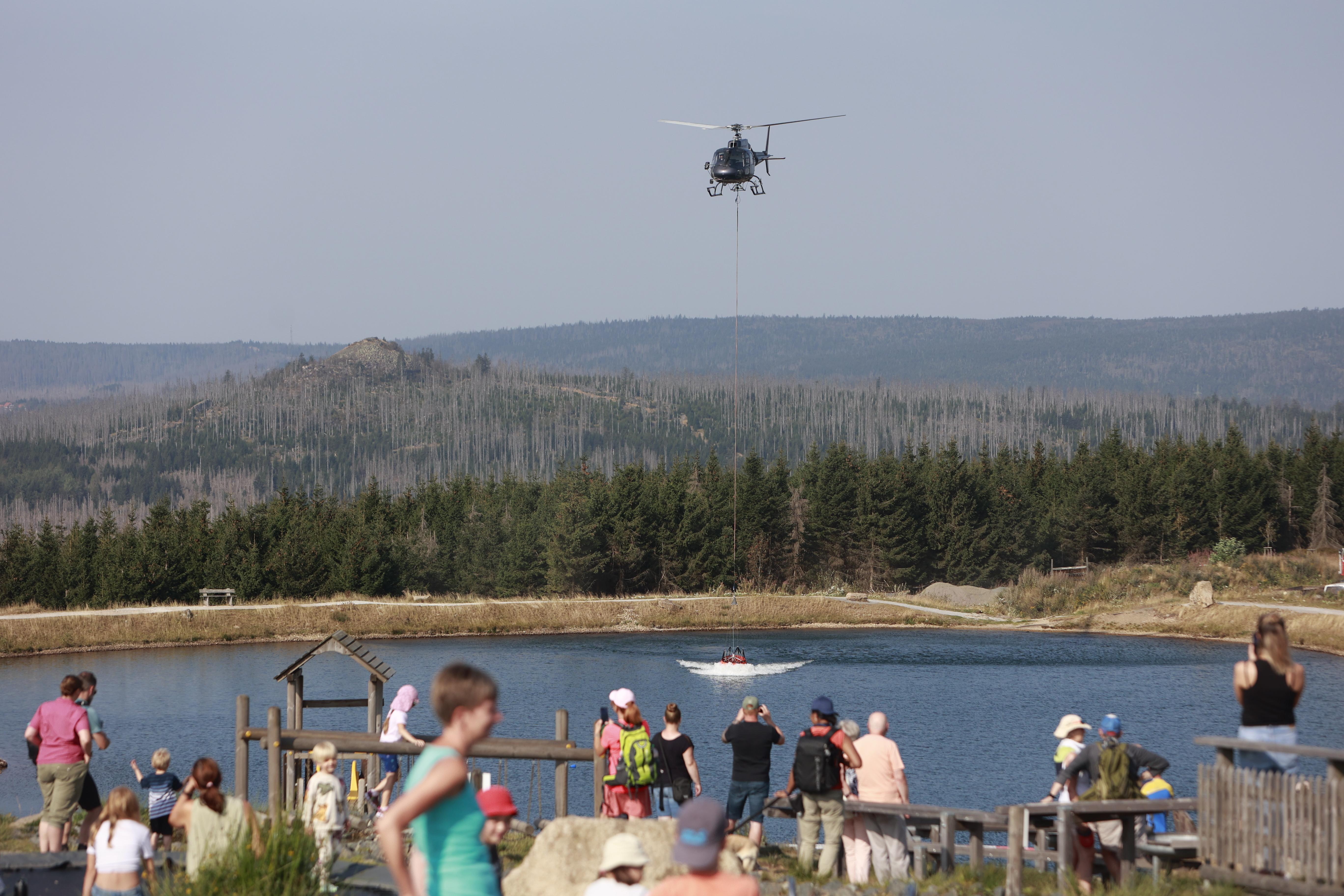 Ein Hubschrauber nimmt am Rückhaltebecken am Torfhaus Wasser für die Waldbrandbekämpfung am Brocken auf.