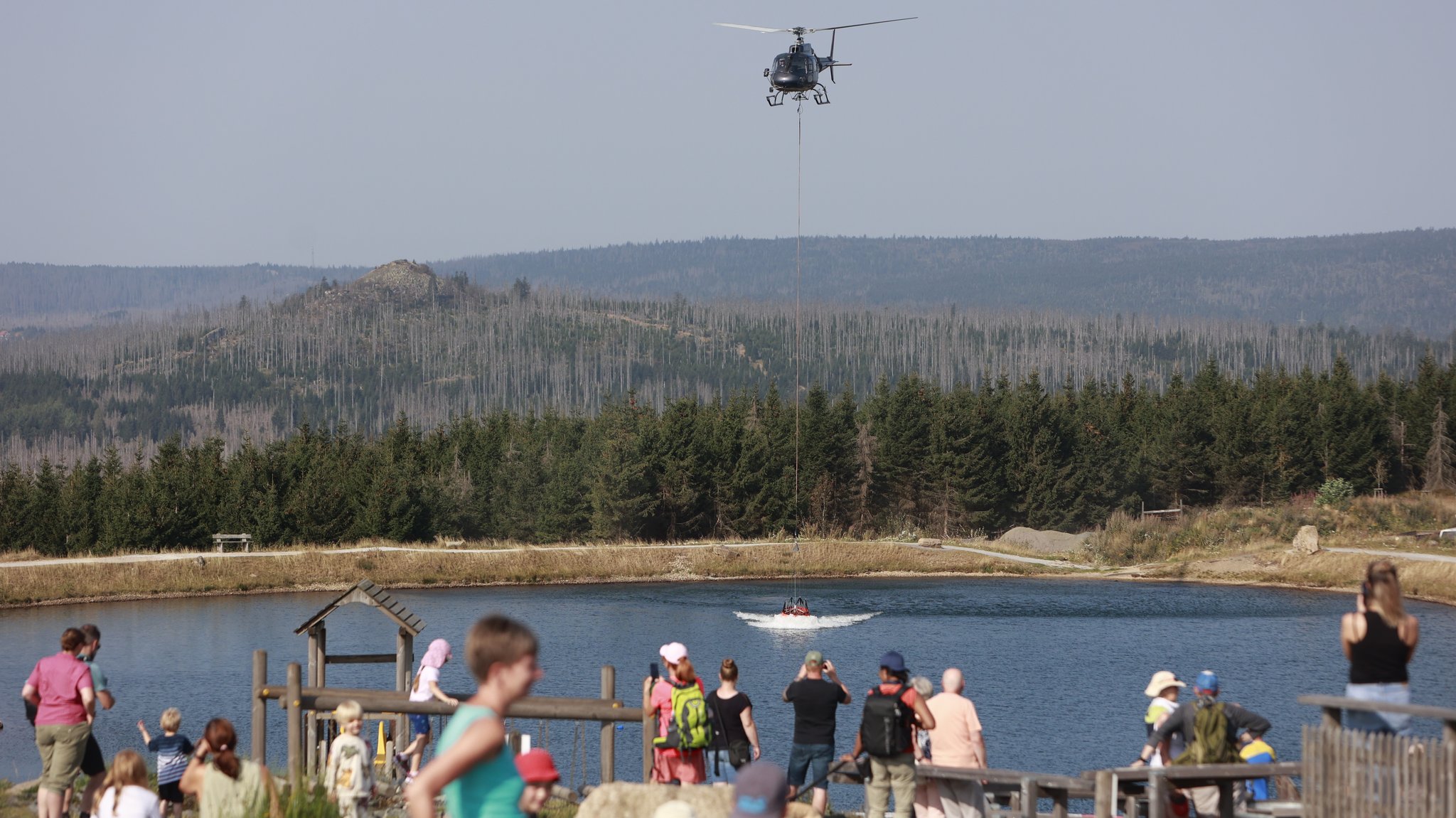 Ein Hubschrauber nimmt am Rückhaltebecken am Torfhaus Wasser für die Waldbrandbekämpfung am Brocken auf.