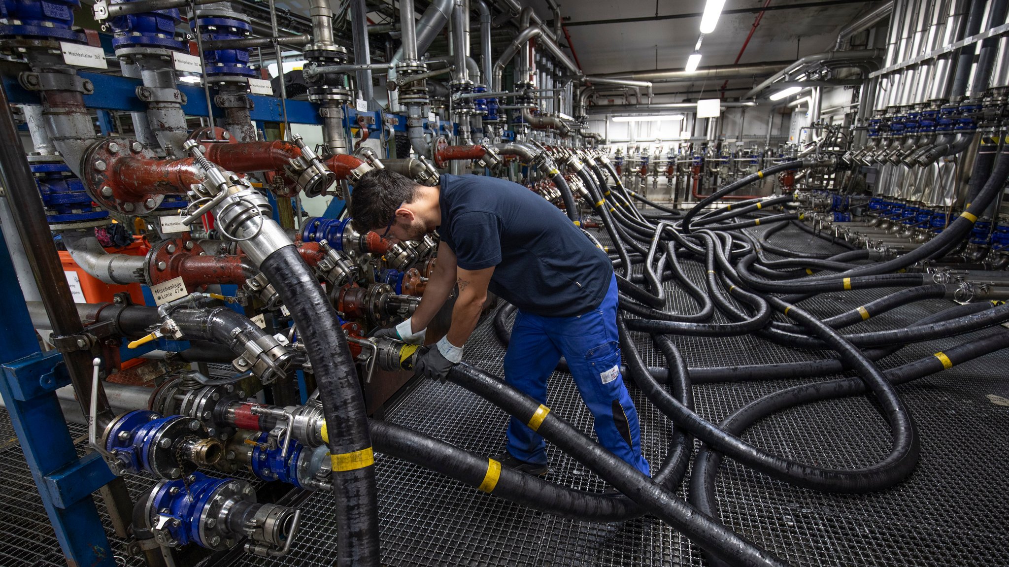Ein Mann schließt in einer Fabrik einen Schlauch an (Symbolbild) | Bild: picture alliance / Ulrich Baumgarten Ein Mann schließt in einer Fabrik einen Schlauch an (Symbolbild)