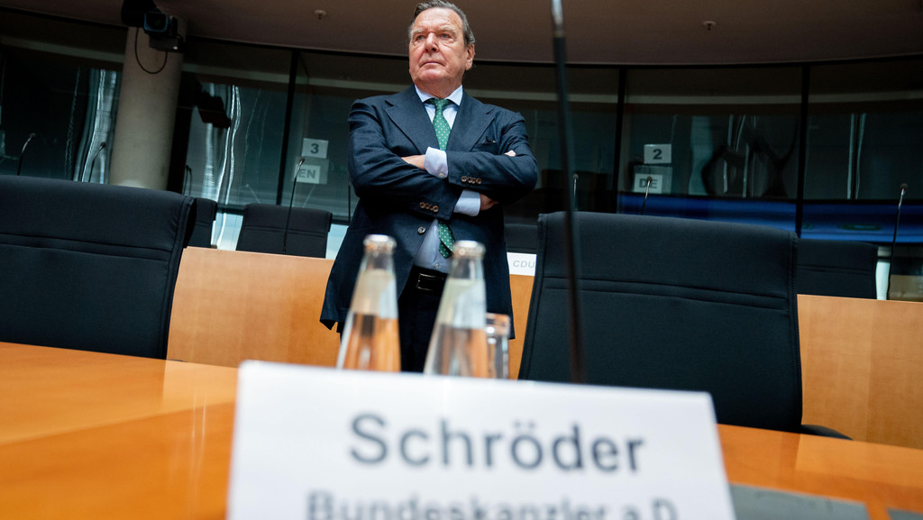 Gerhard Schröder, Bundeskanzler a.D., steht hinter einem Tisch und verschränkt die Arme.