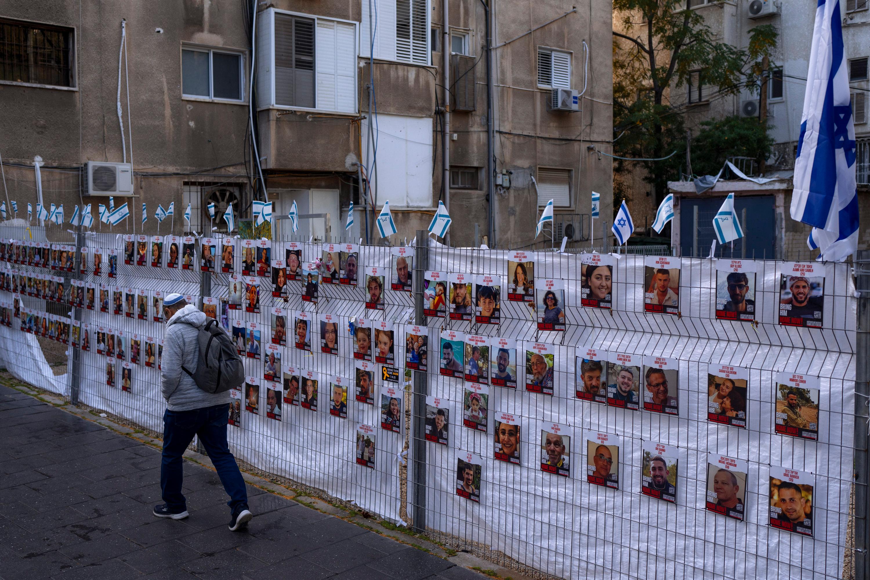 Israel, Ramat Gan: Ein Mann geht an einem Zaun mit Fotos von Geiseln vorbei, meist israelische Zivilisten. | Bild:dpa-Bildfunk/Oded Balilty