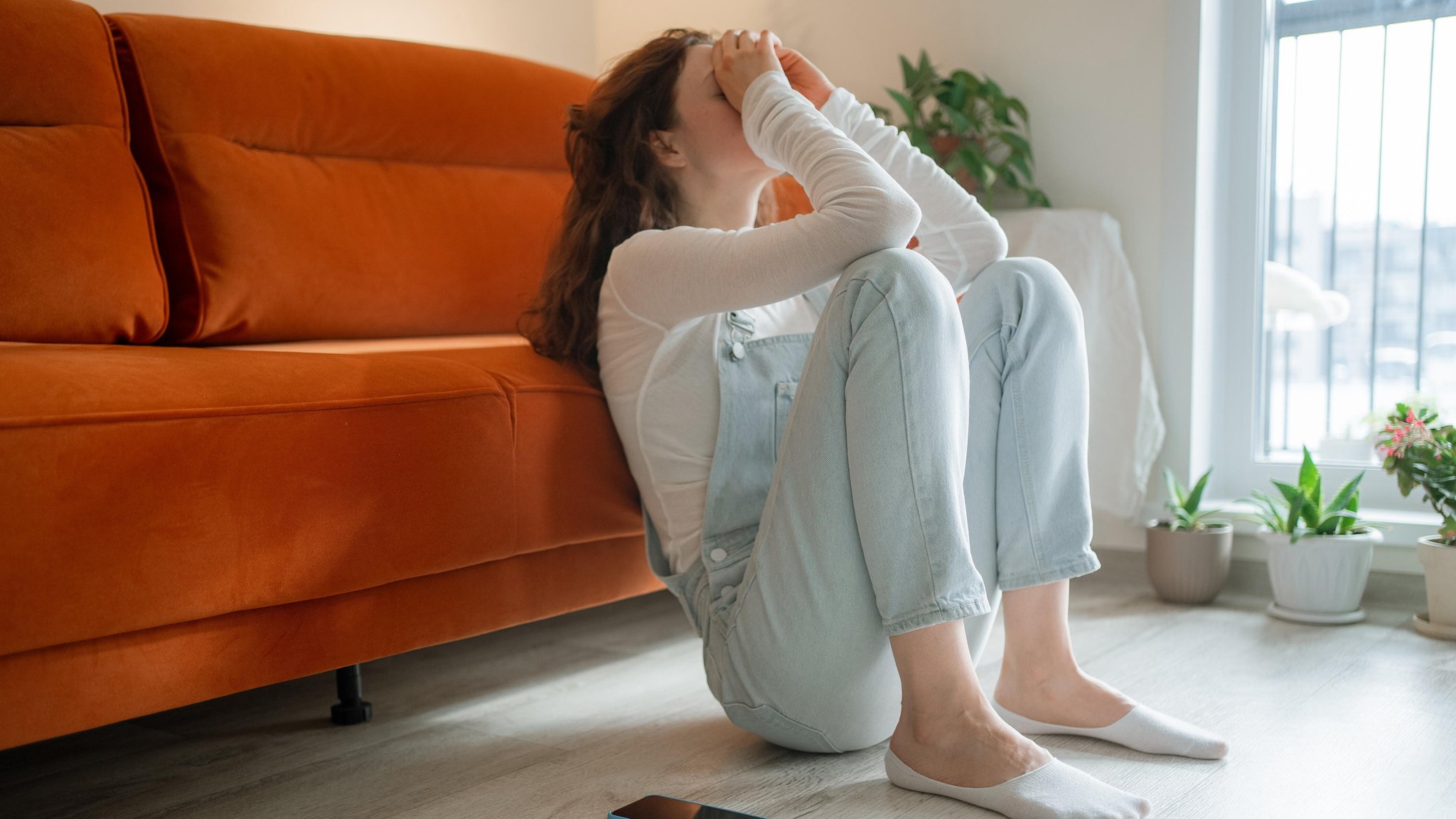Symbolbild: Mädchen hockt vor einer Couch und vergräbt das Gesicht in den Händen. | Bild: picture alliance / Zoonar | Elena Shishkina Symbolbild: Mädchen hockt vor einer Couch und vergräbt das Gesicht in den Händen.