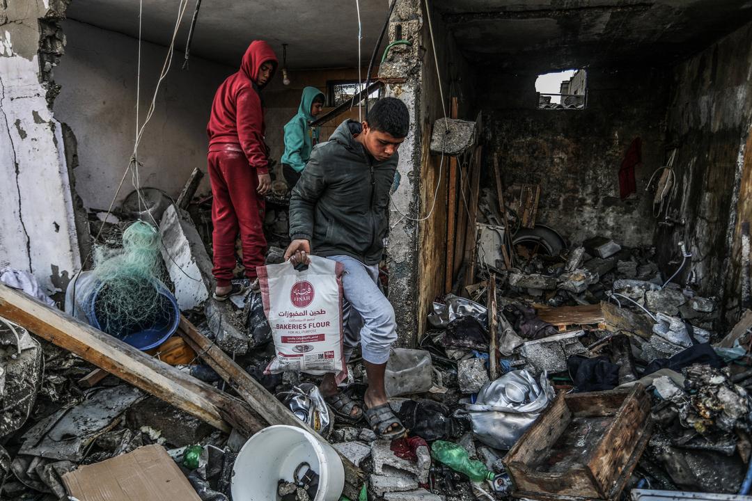Ein palästinensischer Jugendlicher birgt einen Sack Mehl aus einem zerstörten Haus