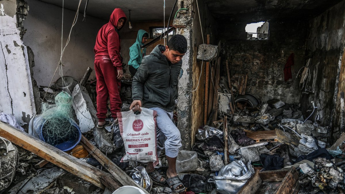 Ein palästinensischer Jugendlicher birgt einen Sack Mehl aus einem zerstörten Haus