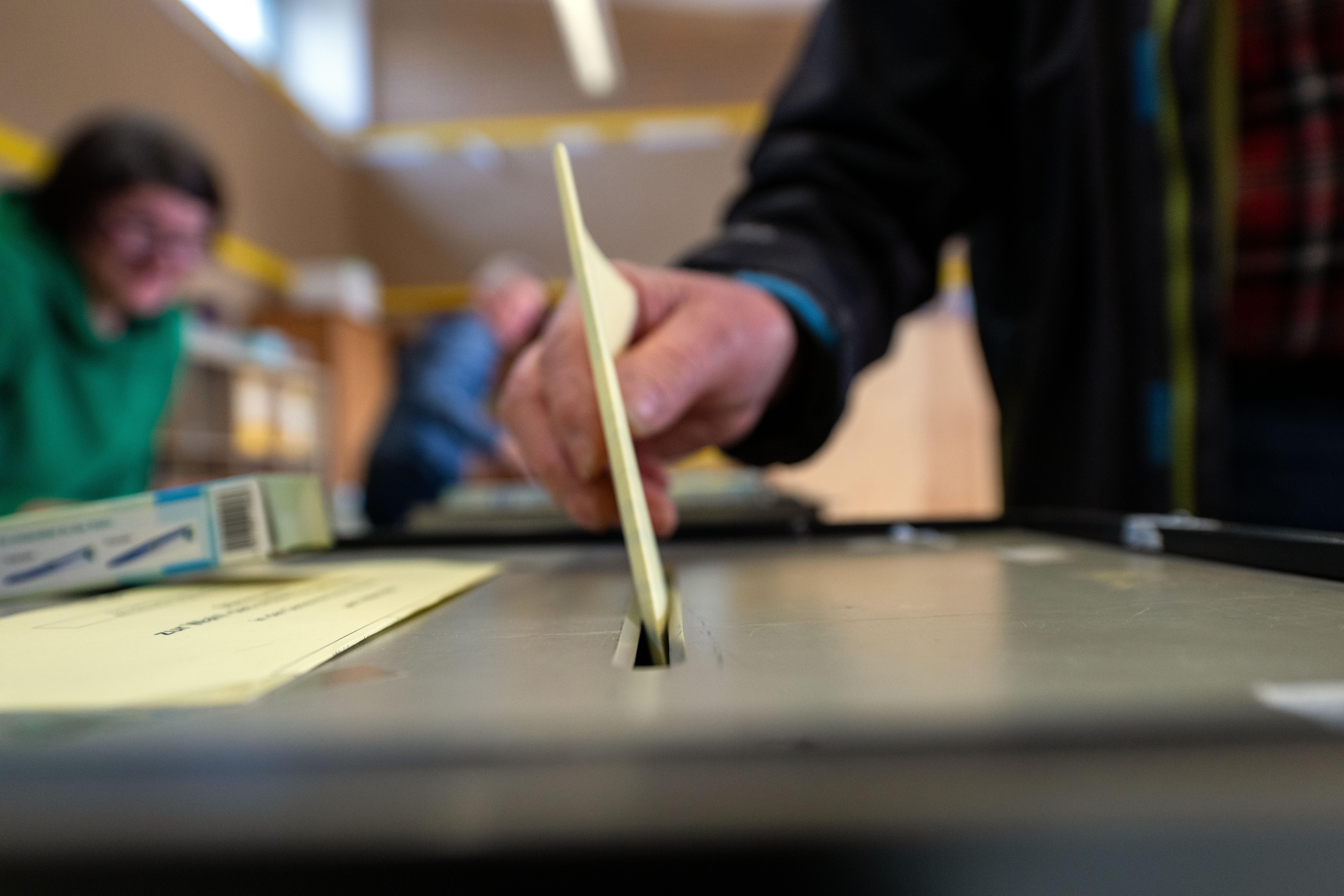 Ein Mann wirft einen ausgefüllten Wahlzettel in eine Wahlurne.