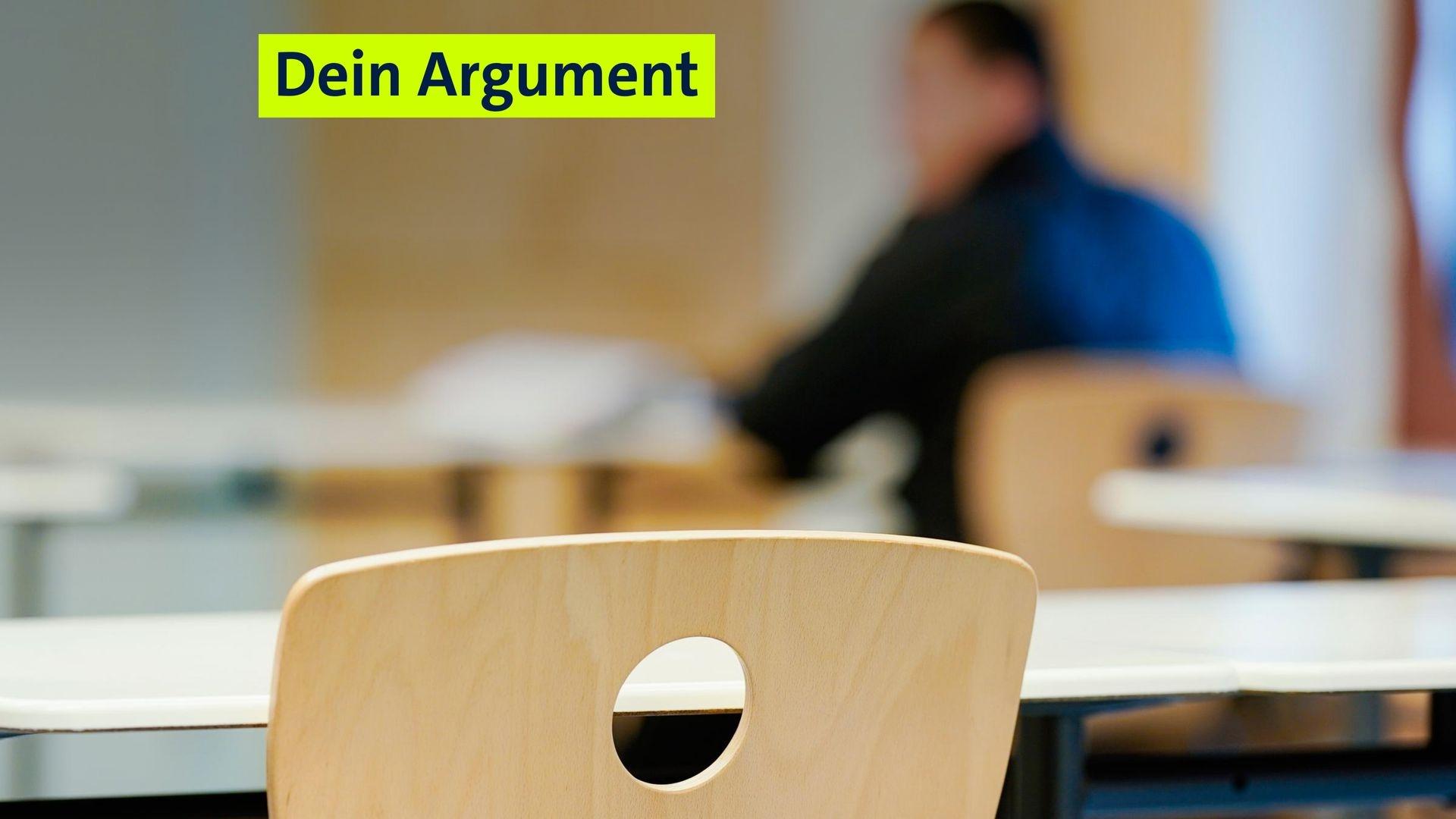 Ein leerer Stuhl in einem Klassenzimmer. An einem Pult weiter vorne sitzt ein Schüler. 