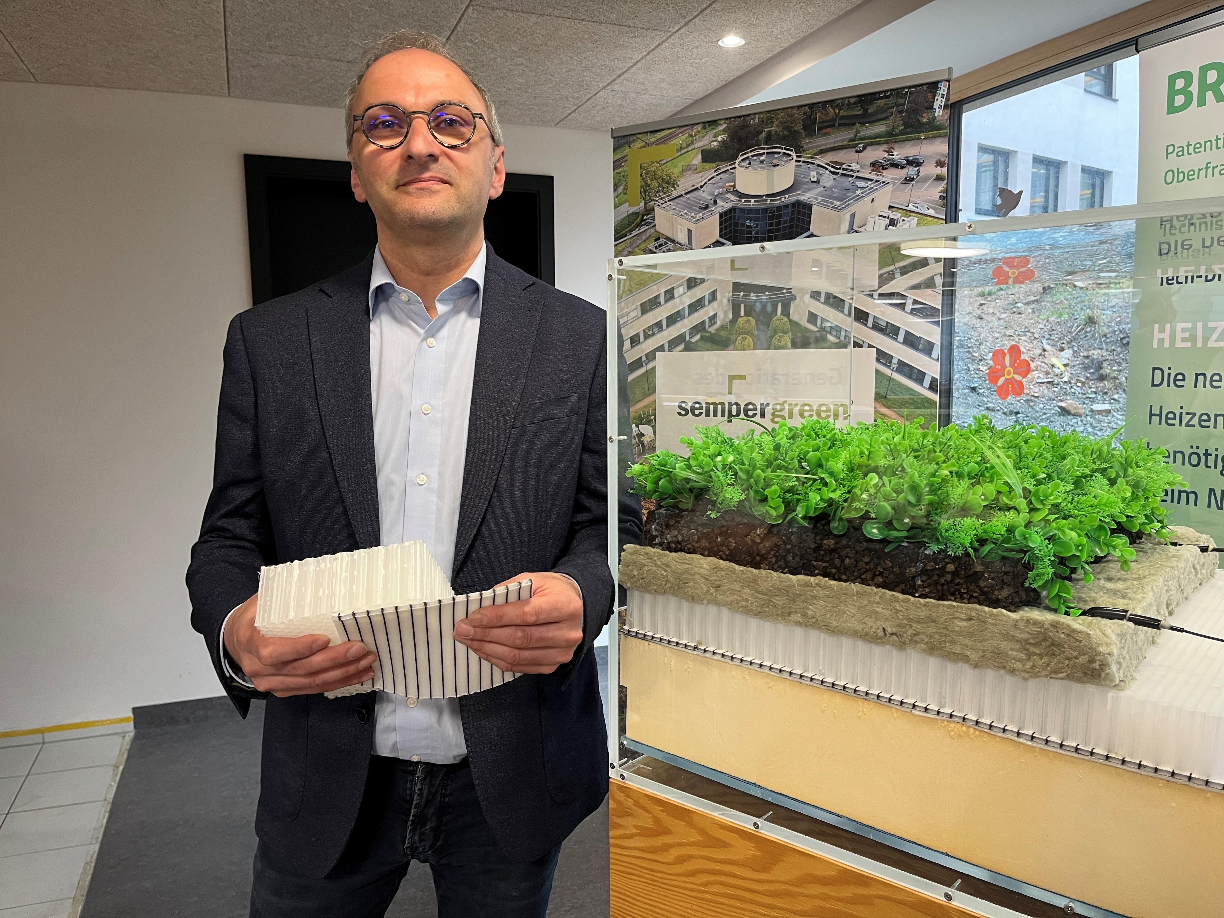 Ein Mann hält ein Vlies und einen Plastikschwamm in der Hand.