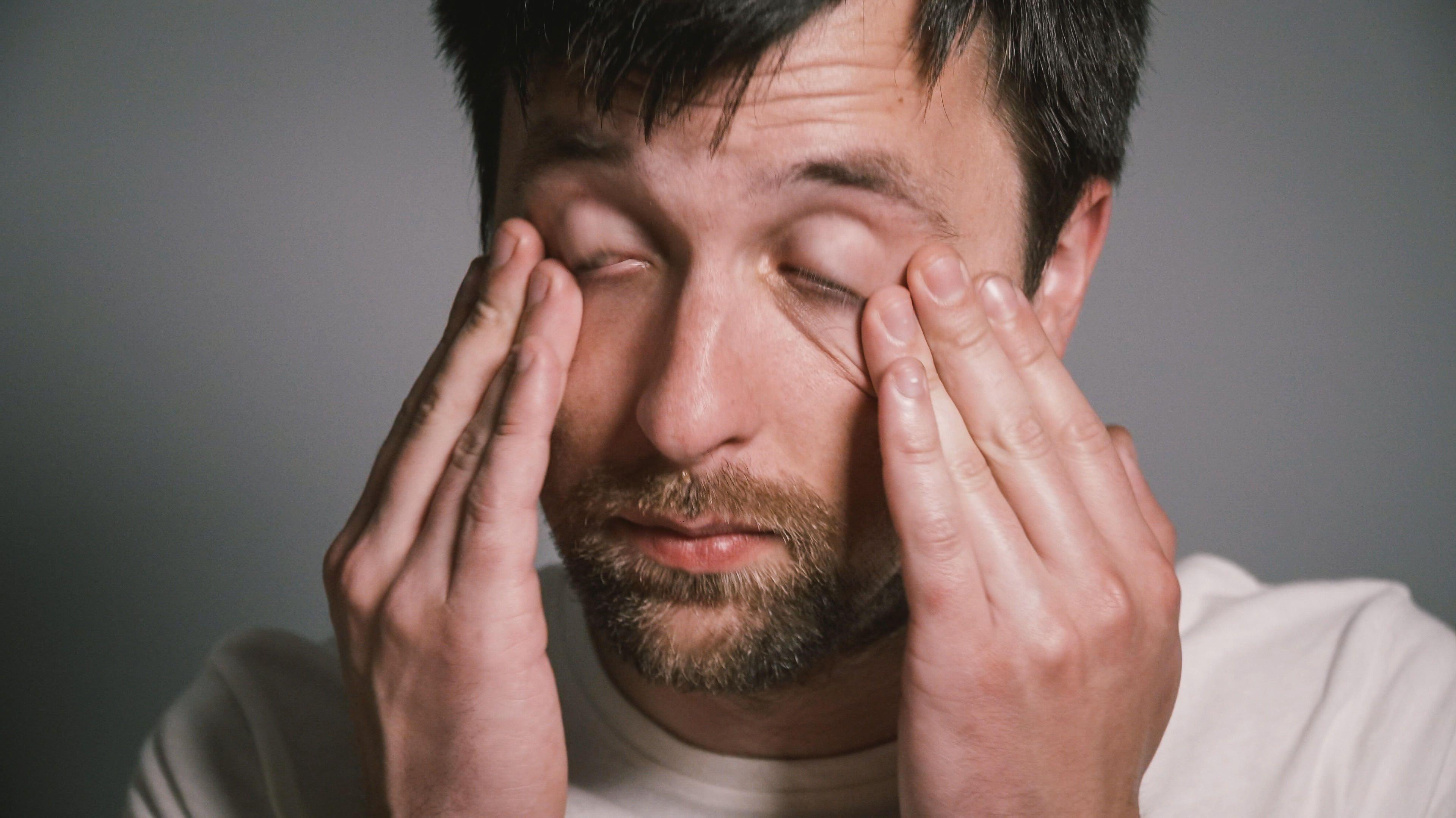 Mann reibt sich erschöpft die Augen.