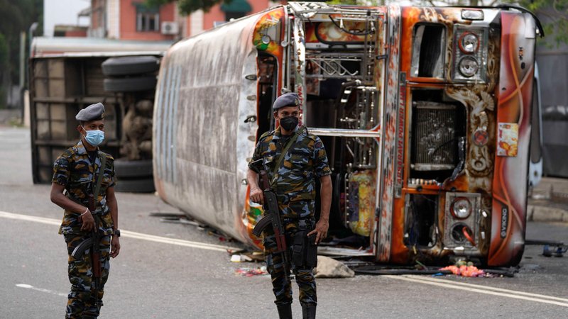 Soldaten der Armee von Sri Lanka stehen in der Hauptstadt Colombo vor einem ausgebranntem Bus Wache.