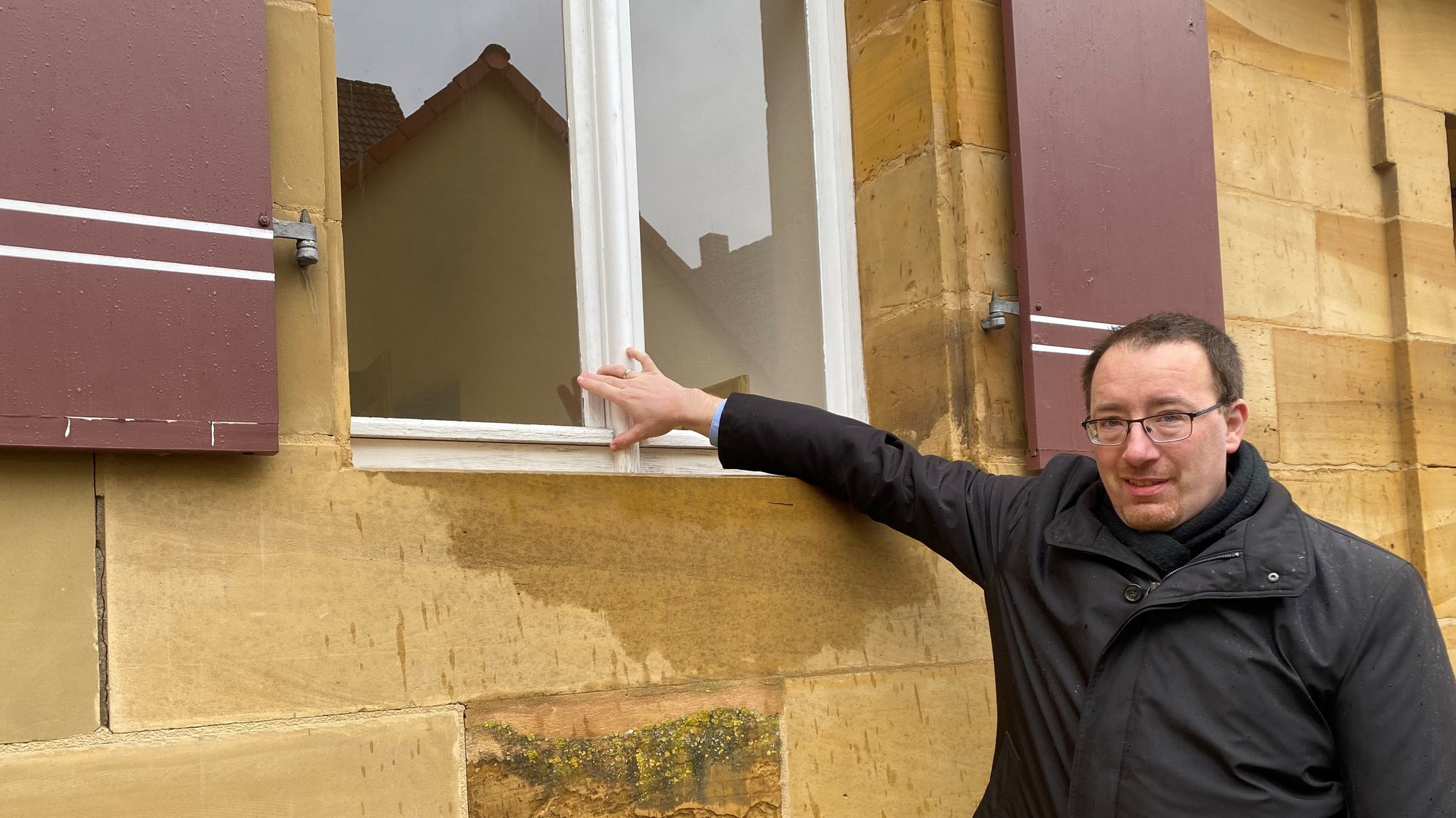 Bürgermeister Martin Walz zeigt auf das Fenster, das eingeschlagen wurde.