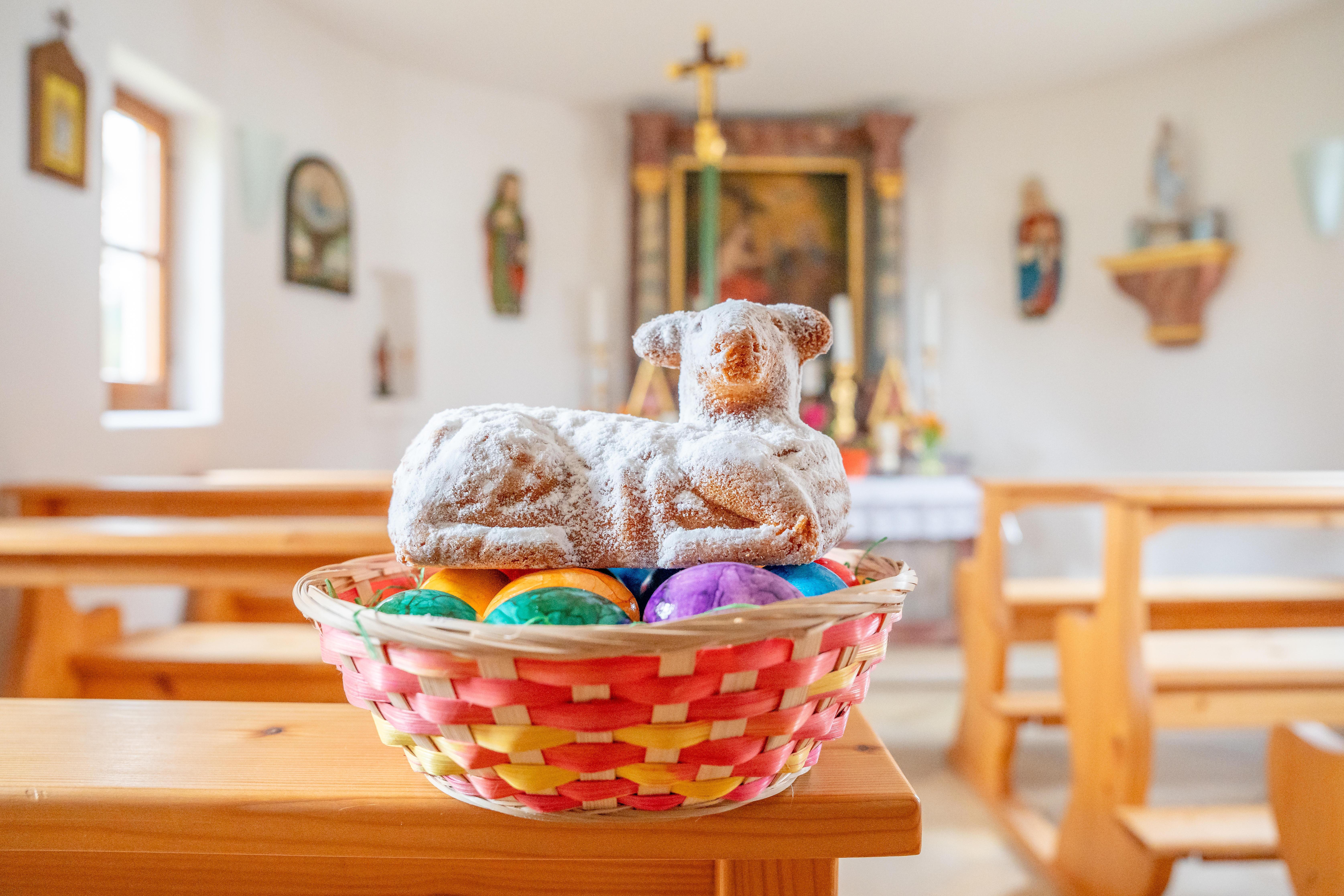 Osterlamm aus Kuchen in einem Osternest mit bunten Eiern in einer Kirche