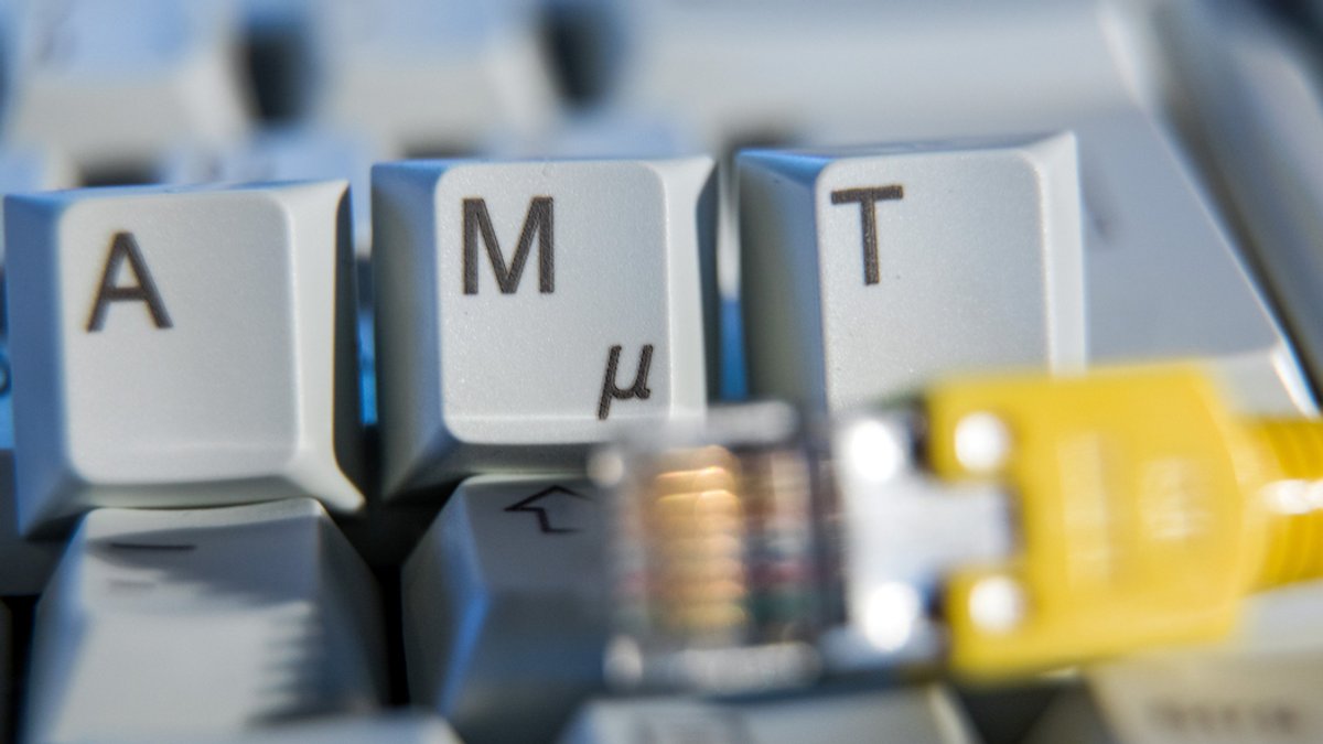 Der Schriftzug "Amt" ist auf einer Computertastatur hinter einem Netzwerkkabel zu sehen