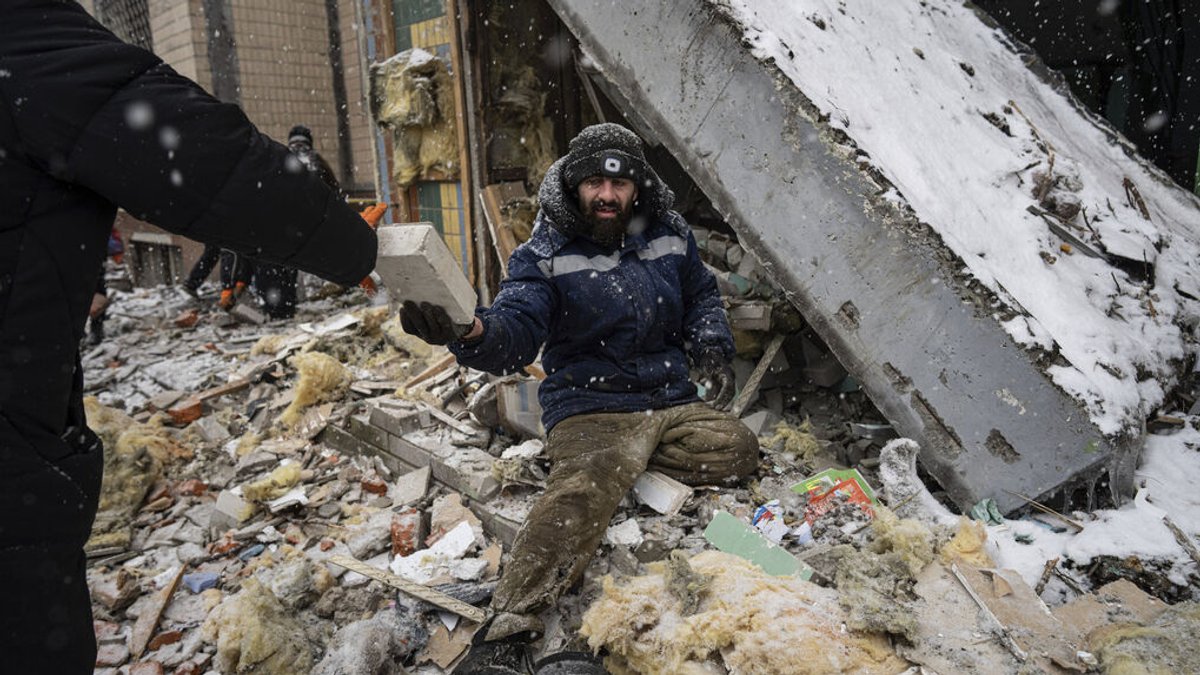 03.01.2024, Ukraine, Kiew: Ein Freiwilliger räumt die Trümmer eines Wohnhauses weg, das gestern bei einem russischen Angriff schwer beschädigt wurde. Foto: Evgeniy Maloletka/AP/dpa +++ dpa-Bildfunk +++