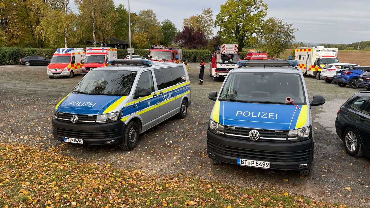 Einsatzfahrzeuge von Polizei, Feuerwehr und Rettungsdienst stehen auf einem Parkplatz nahe einer Realschule in Bayreuth.