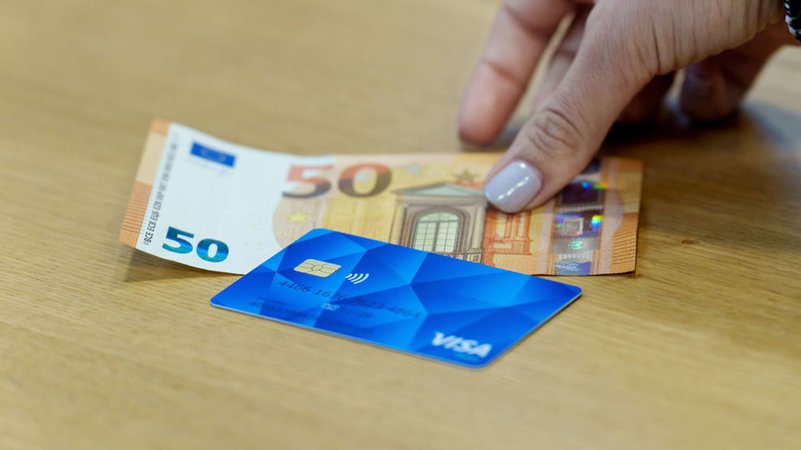 Die Bezahlkarte für Asylbewerberinnen und Asylbewerber und ein 50 Euro Schein liegen nebeneinander. | Bild: dpa-Bildfunk/Andreas Arnold Die Bezahlkarte für Asylbewerberinnen und Asylbewerber und ein 50 Euro Schein liegen nebeneinander.