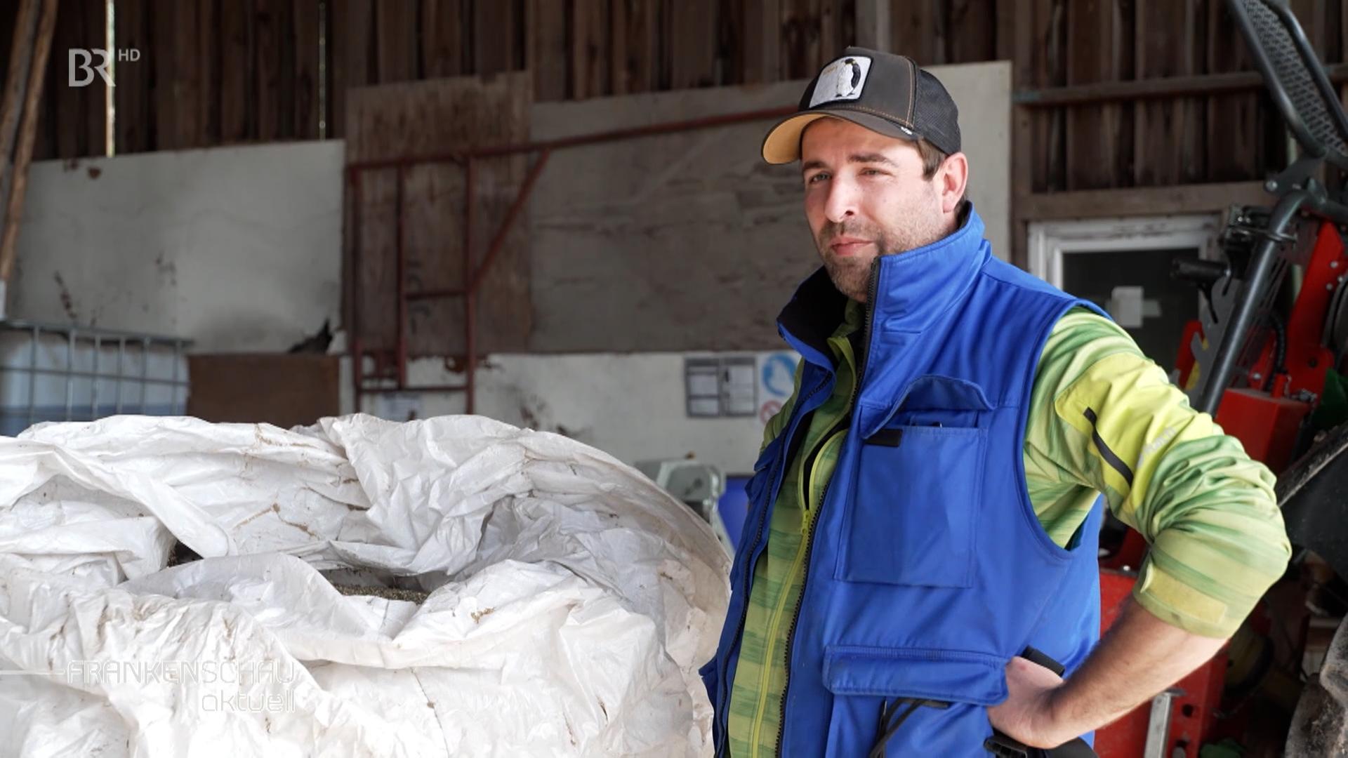 Landwirt Josef Bayer steht vor einem großen Sack Hanfsamen.