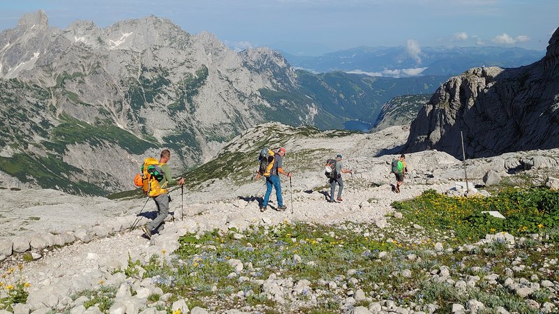 Vier Männer von der DAV Sektion Hof wandern auf einem steinigen Pfad am Dachstein. Im Hintergrund sieht man den Gosaukamm. | Bild: BR / Ulrike Nikola Vier Männer von der DAV Sektion Hof wandern auf einem steinigen Pfad am Dachstein. Im Hintergrund sieht man den Gosaukamm.