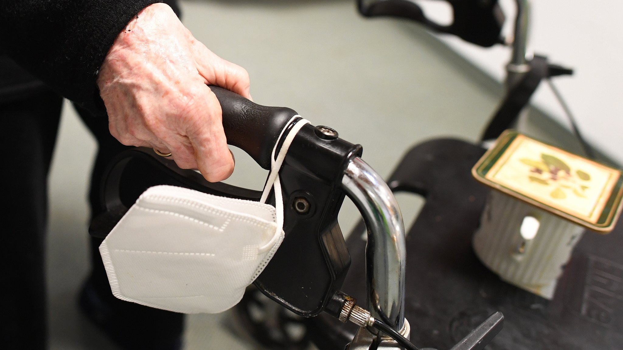 Eine Heimbewohnerin schiebt ihren Rollator mit FFP-2 Maske