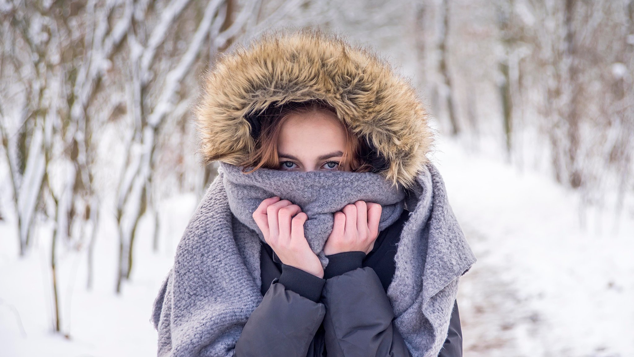 Frau mummelt sich im Schnee in ihren Schal.