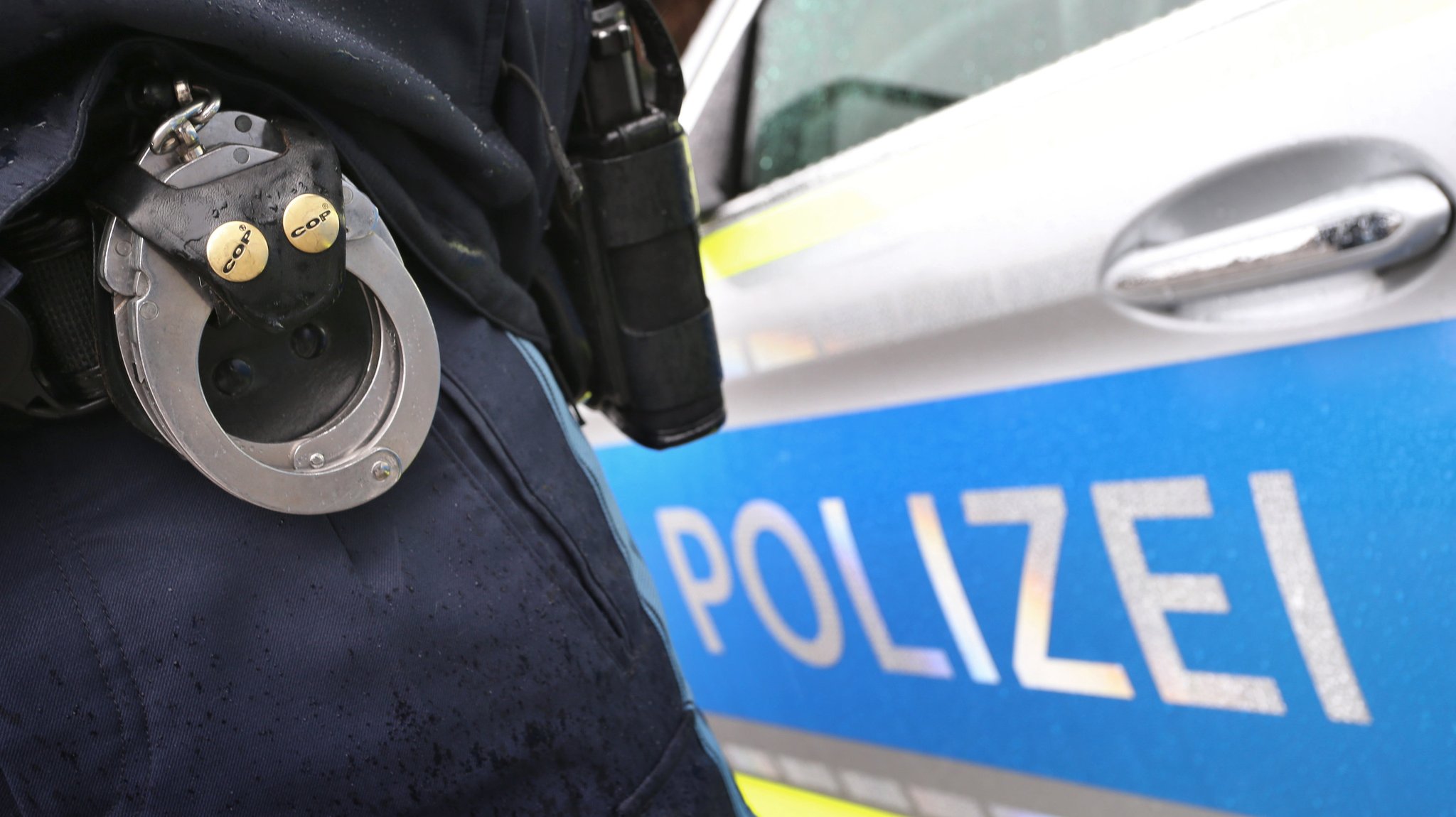 Ein Polizist mit Handschellen und einer Pistole am Gürtel steht vor einem Streifenwagen. | Bild: dpa-Bildfunk/Karl-Josef Hildenbrand Ein Polizist mit Handschellen und einer Pistole am Gürtel steht vor einem Streifenwagen.
