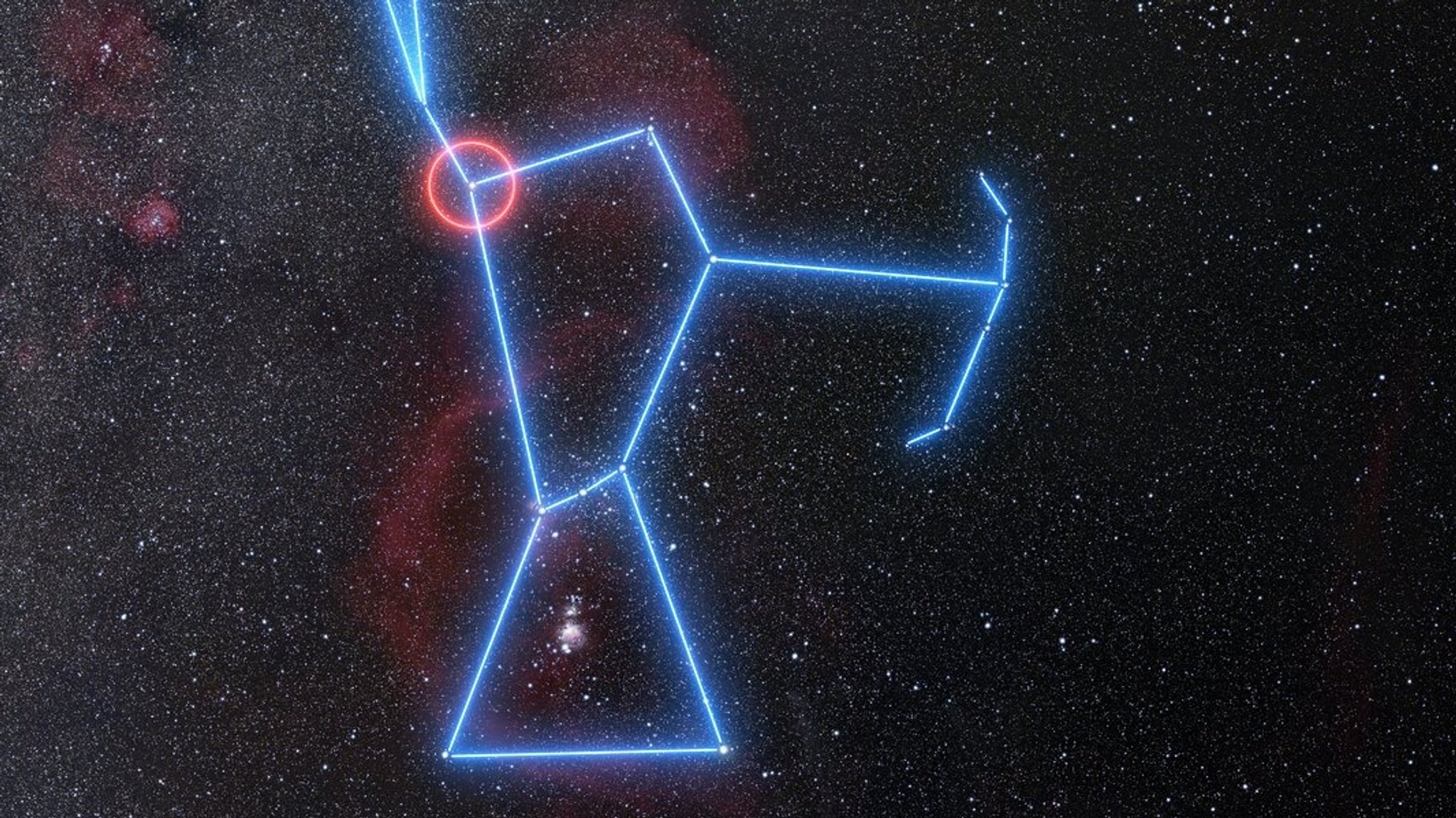 Die Weitwinkelansicht zeigt die Himmelsregion voller Sterne rund um das Sternbild Orion. Orion selbst ist mit blau leuchtenden Linien nachgezeichnet, Beteigeuze ist als Schulterstern mit einem roten Kreis markiert. 