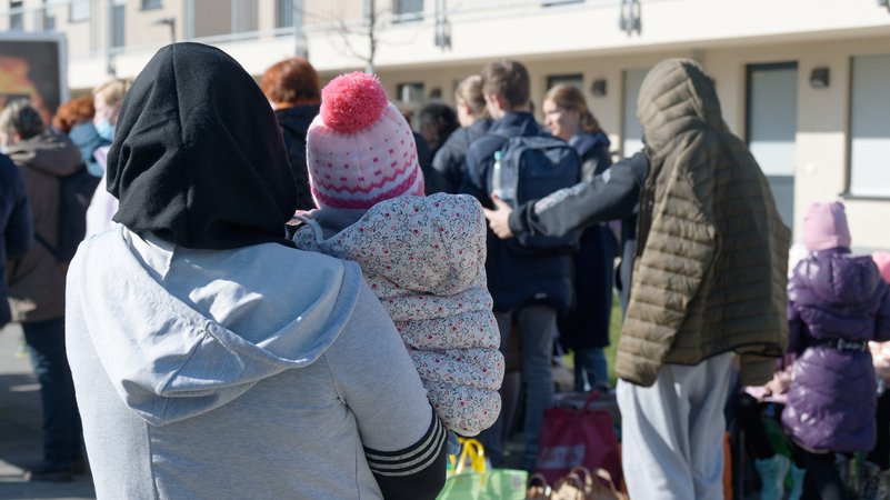 Geflüchtete aus der Ukraine stehen mit ihrem Gepäck vor den Gebäuden eines Flüchtlingsheims.