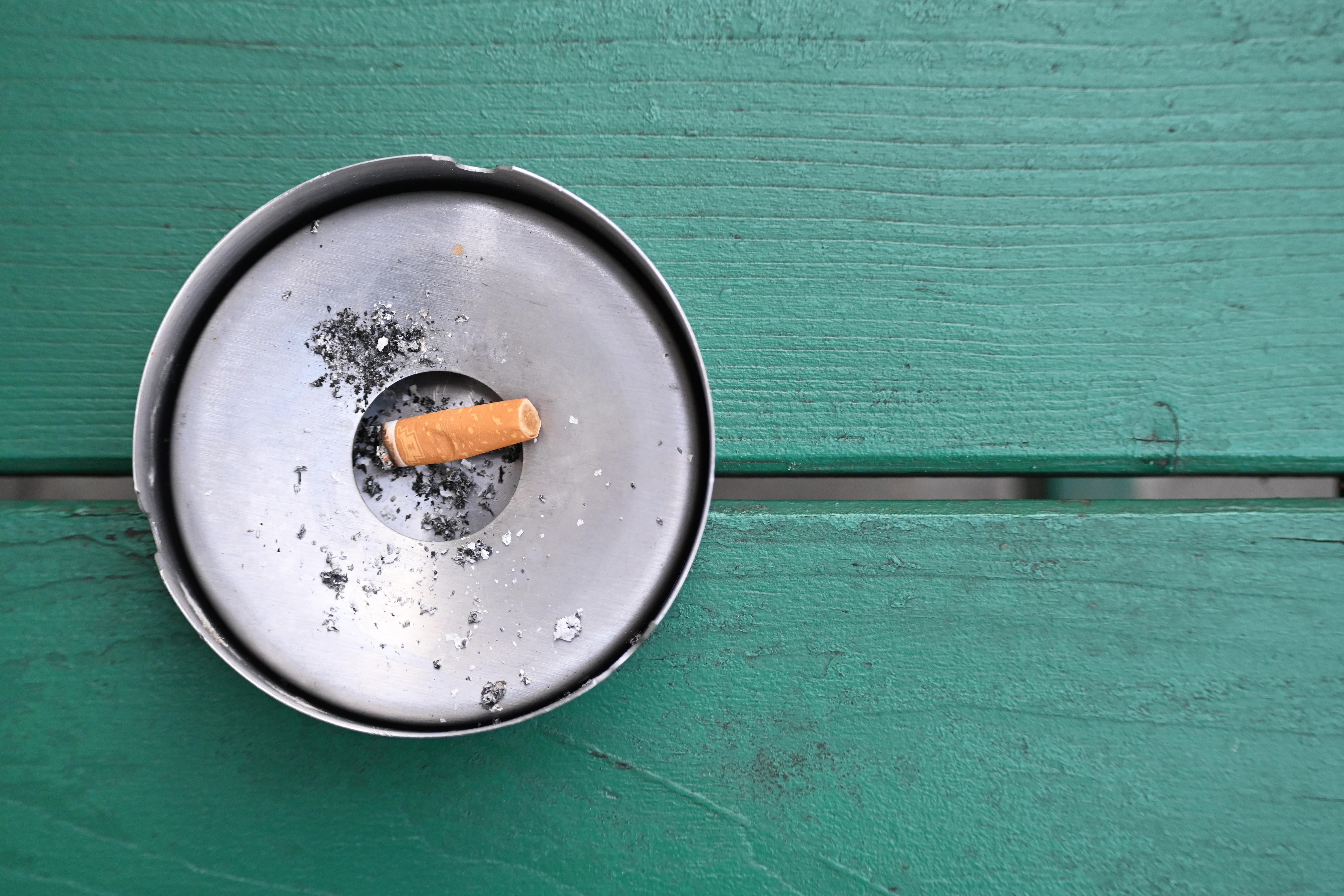 Im Freien liegt eine abgebrannte Zigarette in einem Aschenbecher. 