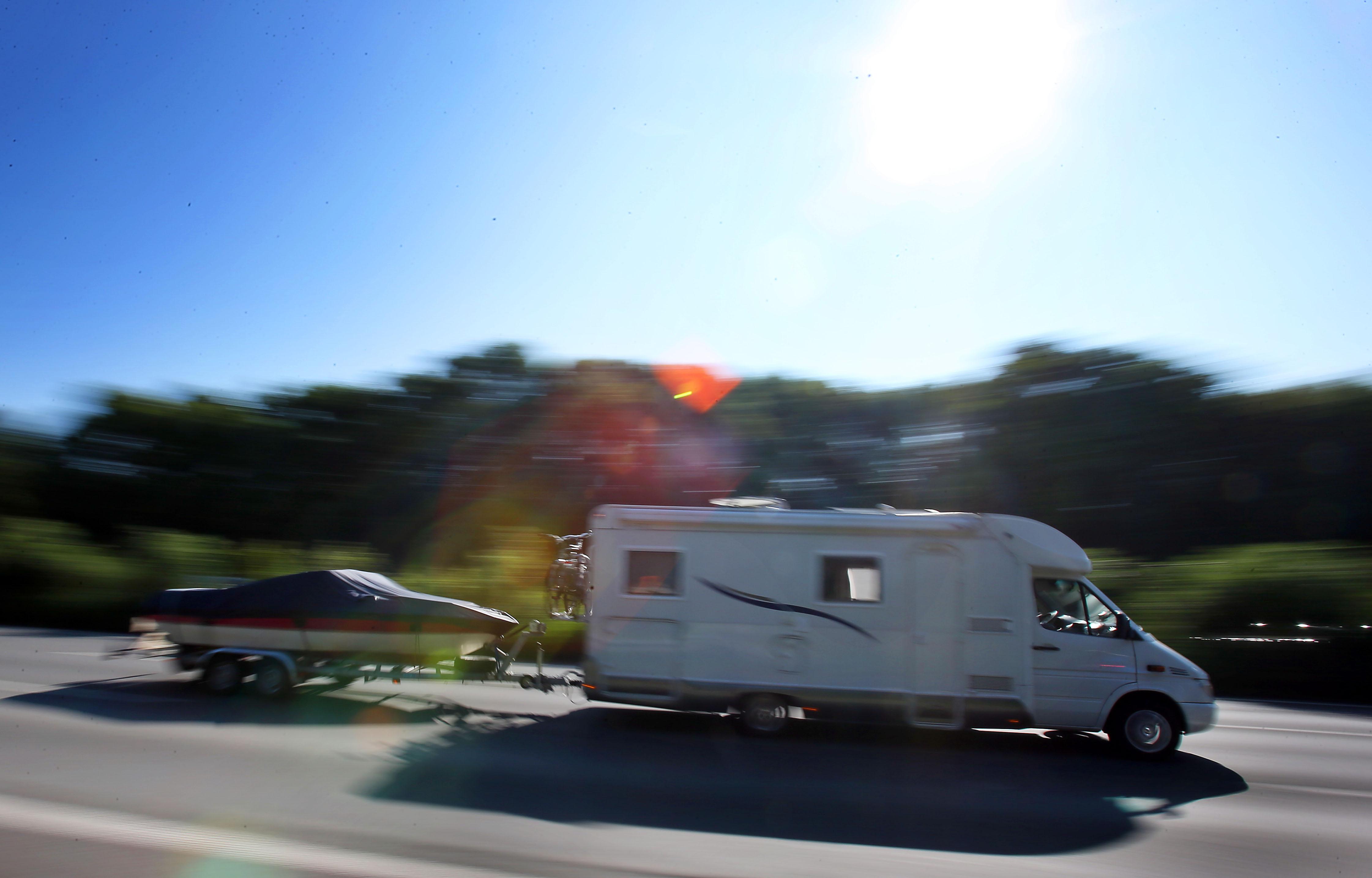 Ein Wohnmobil zieht einen Bootsanhänger hinter sich her