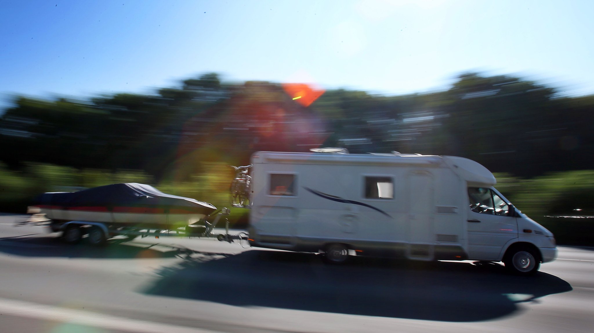 Ein Wohnmobil zieht einen Bootsanhänger hinter sich her