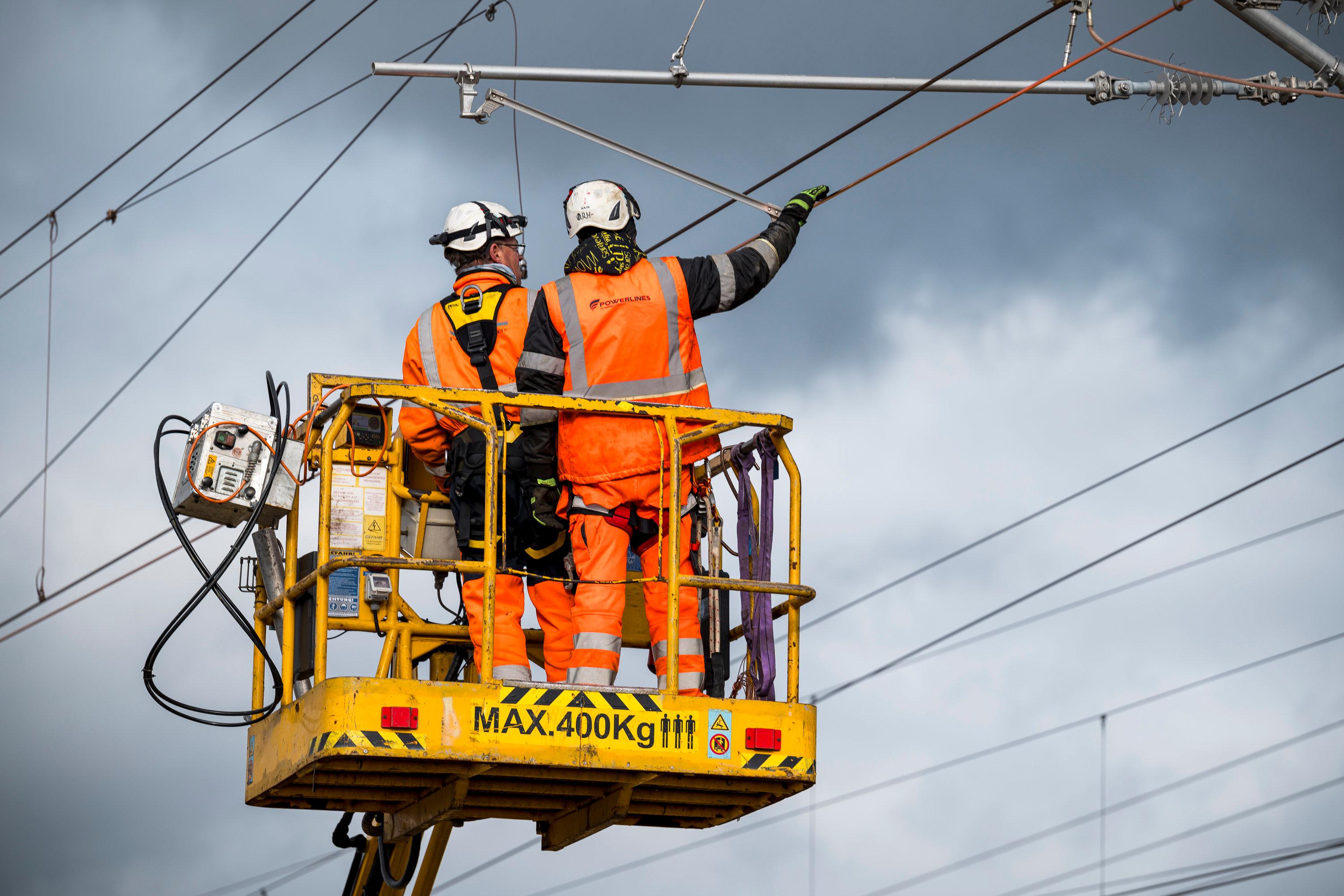  Zwei Arbeiter installieren neue Oberleitungen