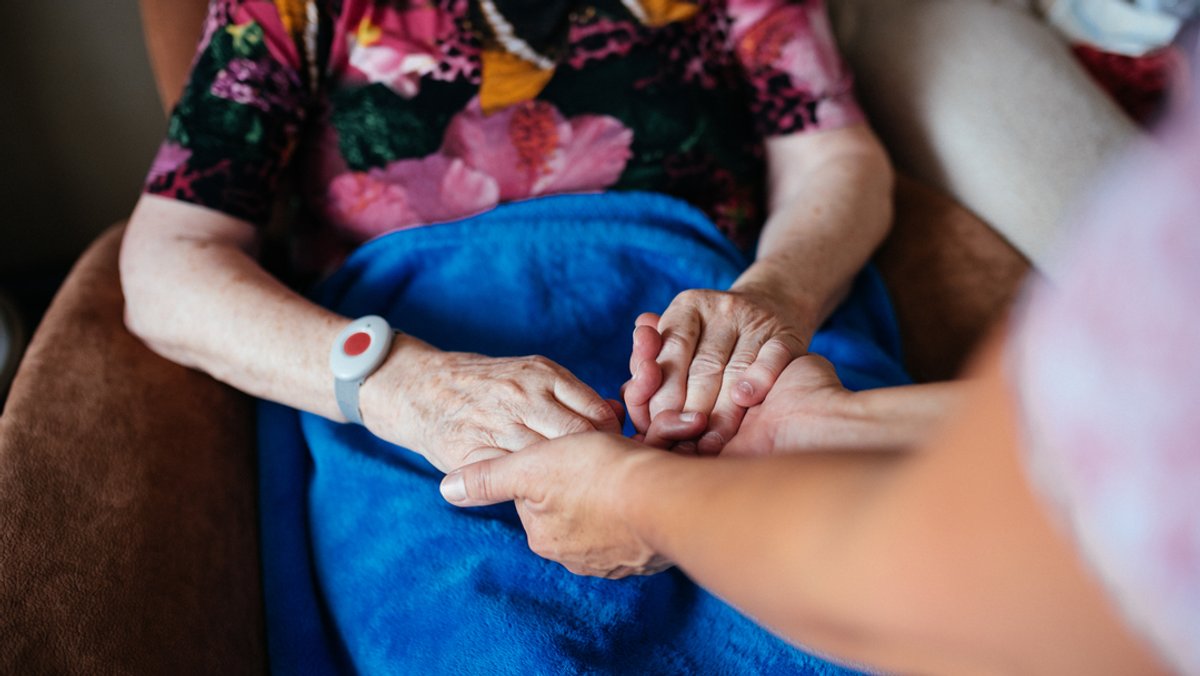 Eine Pflegekraft hält die Hände einer älteren Frau