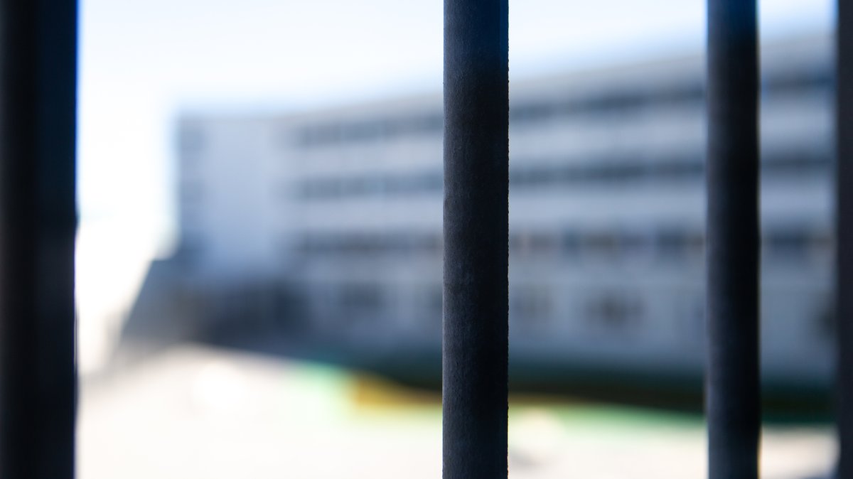 Blick durch die Gitterstäbe einer Gefängniszelle in den Gefängnishof.