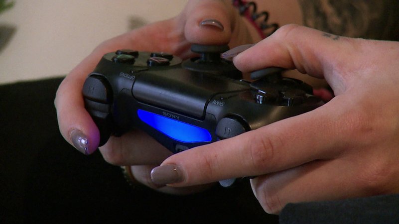 Eine Frau hält eine Computerspiel-Konsole. | Bild: BR/SWR Eine Frau hält eine Computerspiel-Konsole.