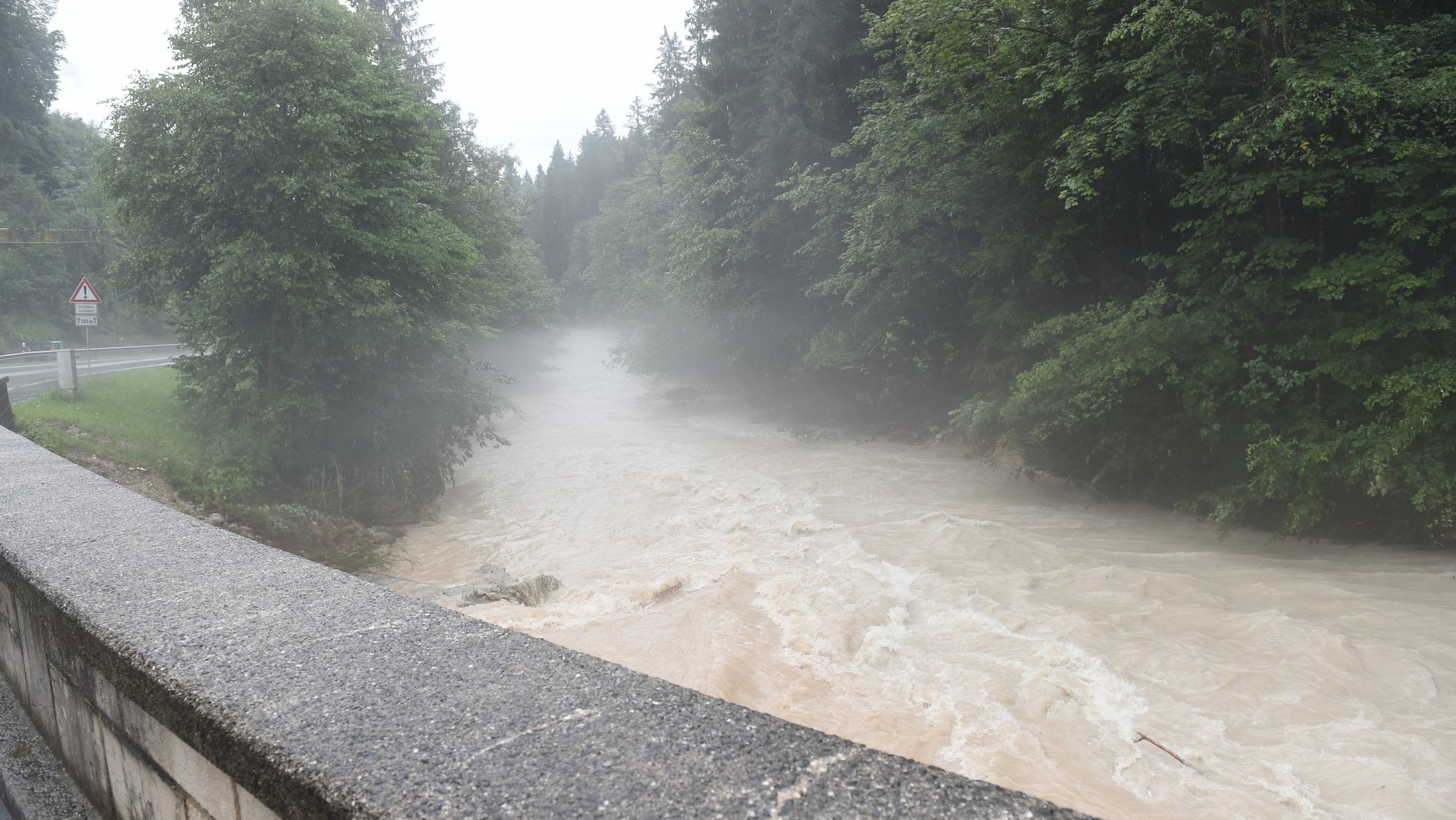 Ein Fluss an der Straße Richtung Königssee ist bei Unwetter und Hochwasser in Bayern im Berchtesgadener Land überflutet.