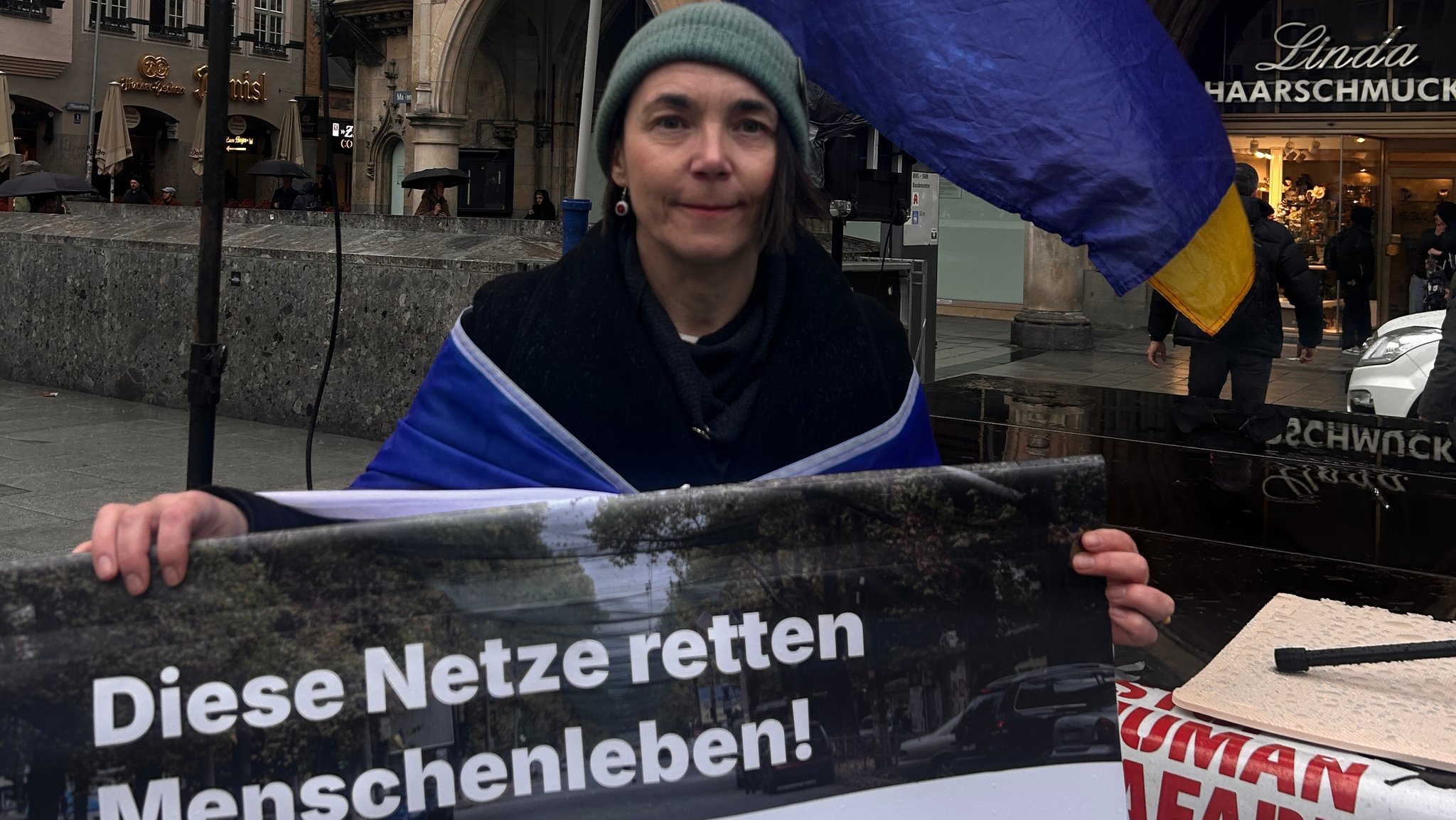 Ukrainierin die ein Schild hochhält mit der Aufschrift: "Diese Netze retten Menschenleben"