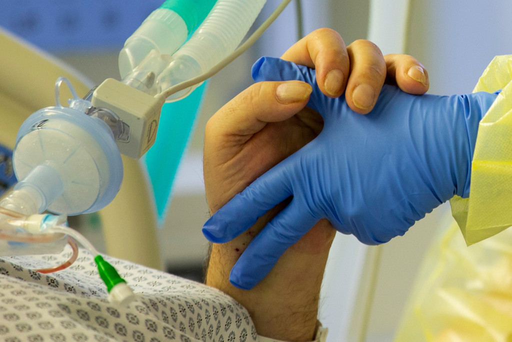 Eine Krankenschwester hält die Hand eines Covidpatienten auf der Intensivstation eines Krankenhauses. (Symbolbild)