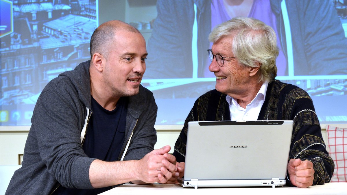 Zwei Männer am Tisch vor einem silbernen Laptop