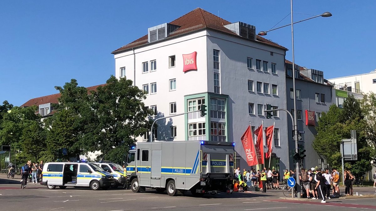 Polizei und Schaulustige an der stark frequentierten Kreuzung in Regensburg. Mehrere Klimaaktivisten haben sich auf der Fahrbahn festgeklebt.