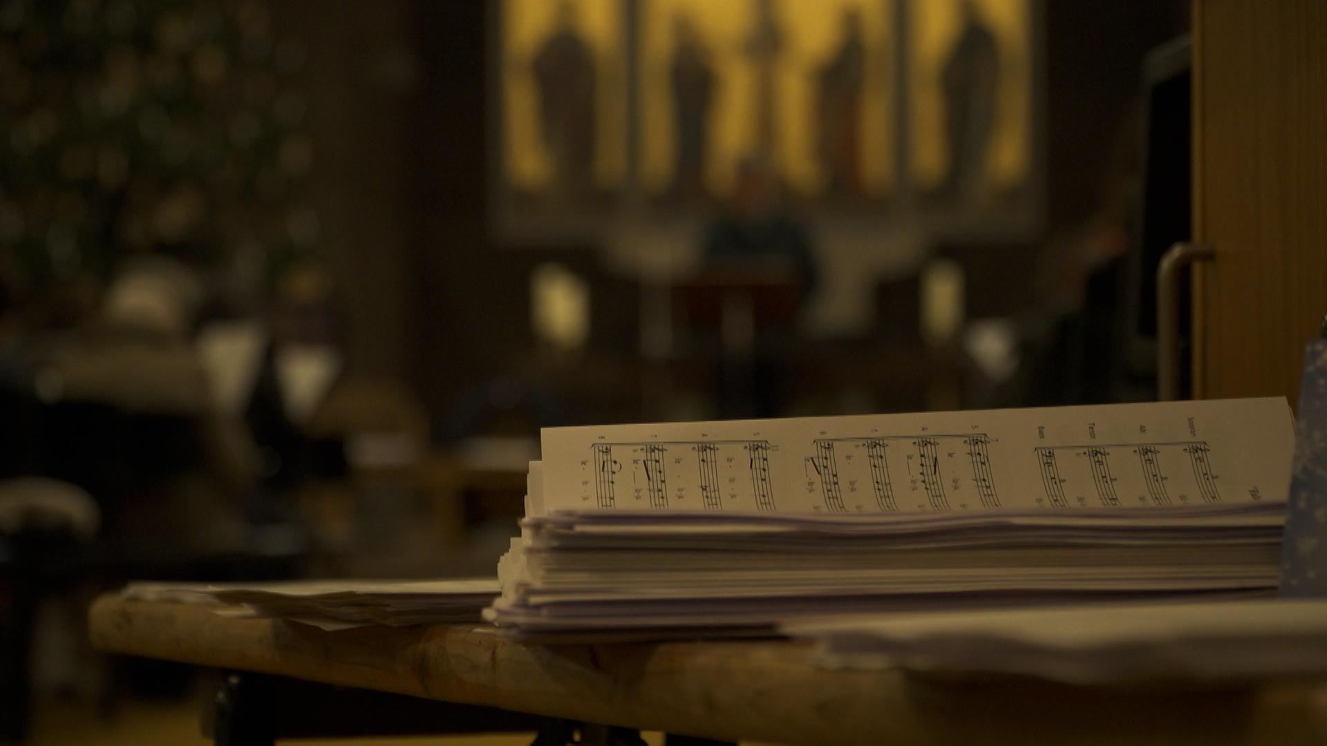 Notenblätter liegen gestapelt am Eingang einer Kirche.