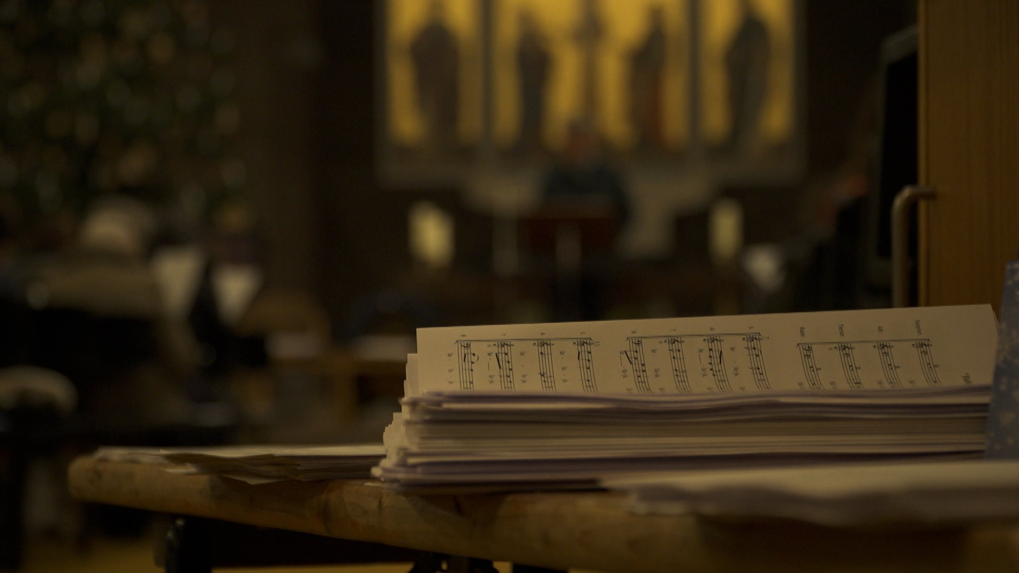 Notenblätter liegen gestapelt am Eingang einer Kirche.