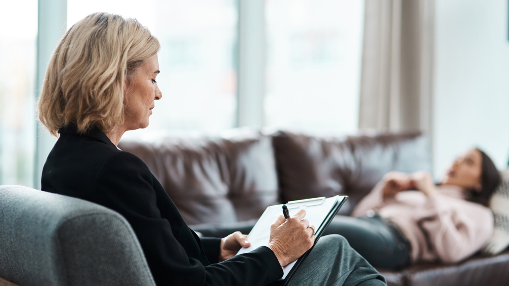 Eine Psychotherapeutin, die während einer Therapiesitzung mit ihrer Patientin Notizen macht.