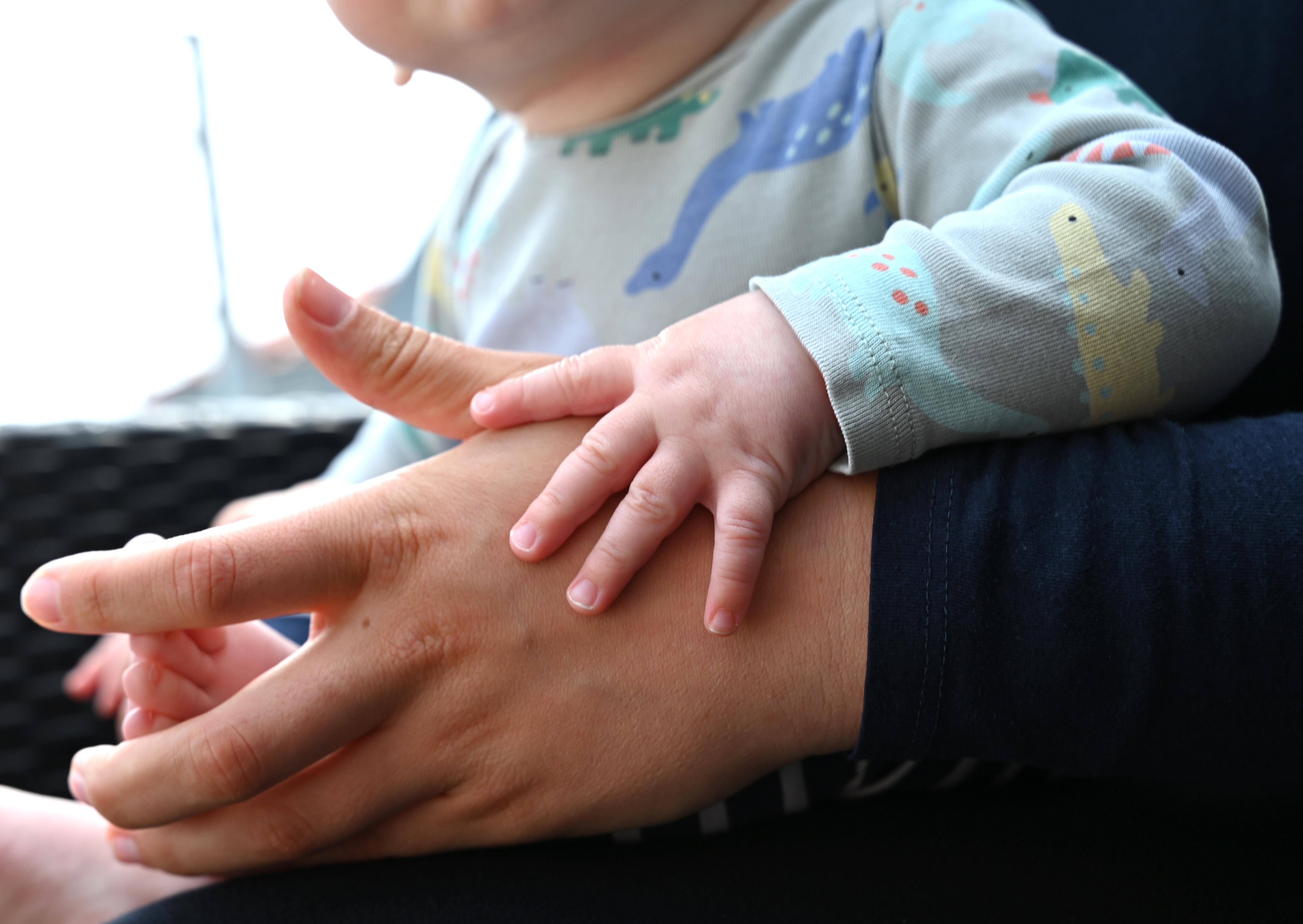 Hand eines Babys auf der Hand der Mutter (Symbolbild)