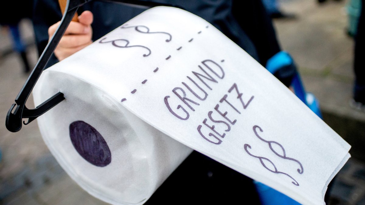 Bei einer "Querdenken"-Demo hält eine Teilnehmerin eine gebastelte Toilettenpapierrolle mit der Aufschrift "Grundgesetz" (Archivbild 21.11.20)