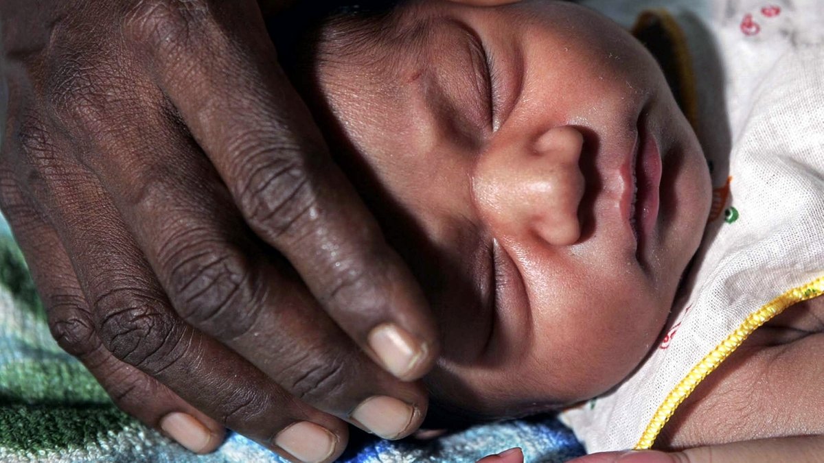 Ein Mutter in Sri Lanka legt die Hand auf die Stirn ihres zwei Tage alten Kindes. 