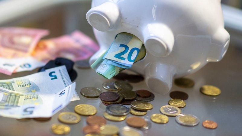 Geld steckt im Bauch eines Sparschweins. | Bild: dpa-Bildfunk/Hendrik Schmidt Geld steckt im Bauch eines Sparschweins.