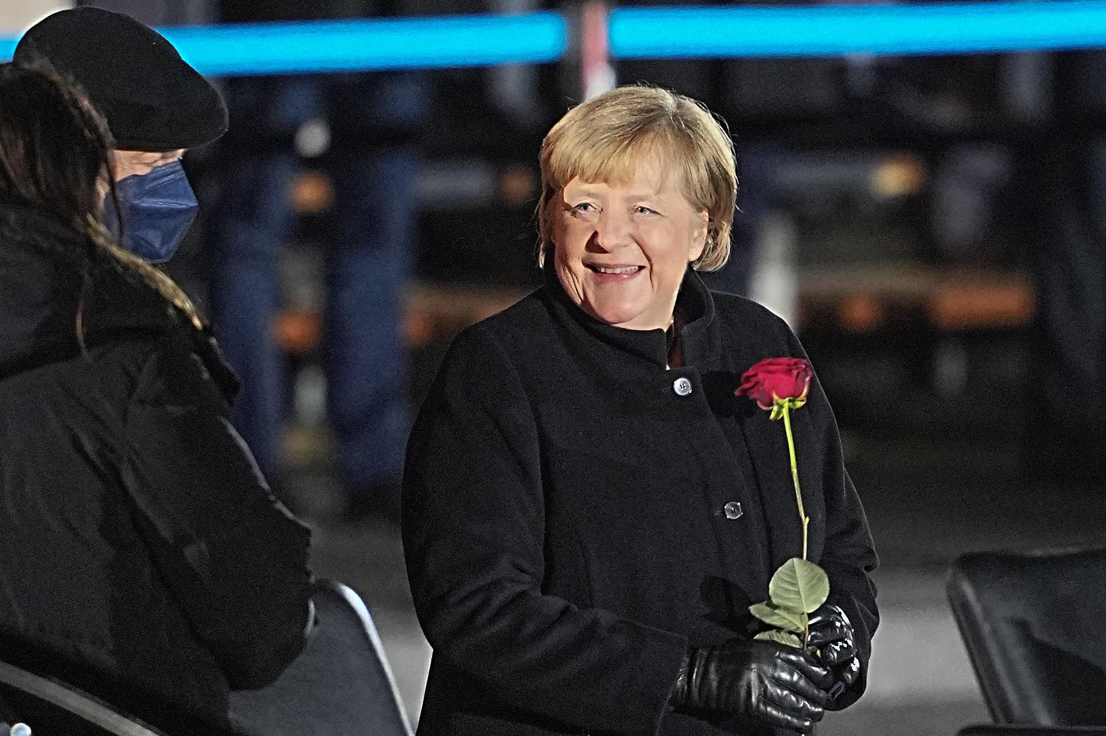 02.12.2021, Berlin: Bundeskanzlerin Angela Merkel (CDU) lacht nach ihrer Verabschiedung durch die Bundeswehr mit einer Rosen in der Hand neben ihrem Mann, Joachim Sauer. Mit einem Großen Zapfenstreich wird Kanzlerin Merkel gegen Ende ihrer Regierungszeit nach 16 Jahren im Bendlerblock verabschiedet